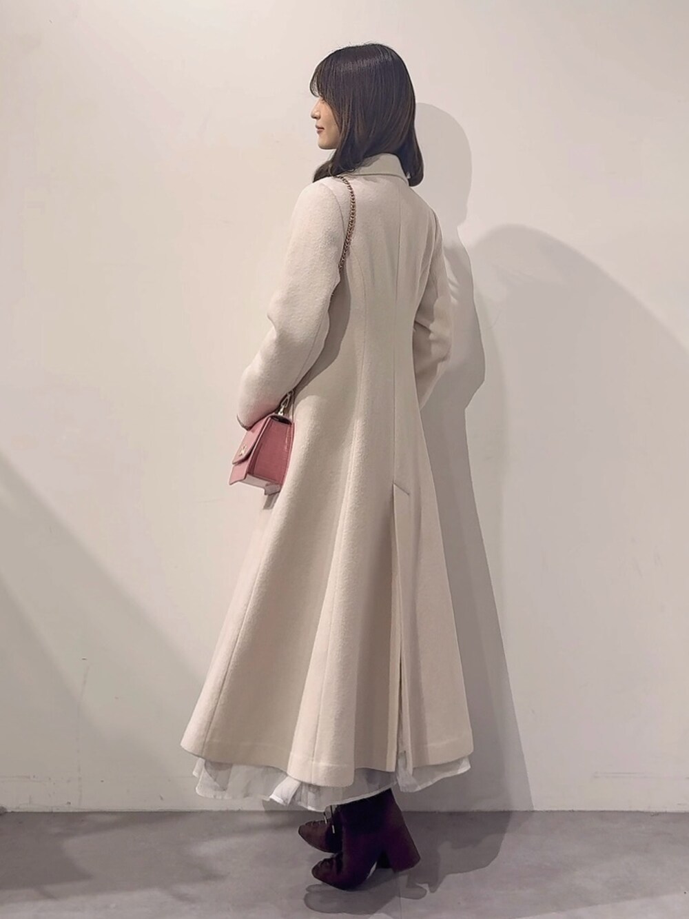 ホワイト系のその他アウター、ピンク系のハンドバッグ、ブラウン系のブーツを着用したレディースの秋コーディネートの4枚目の写真