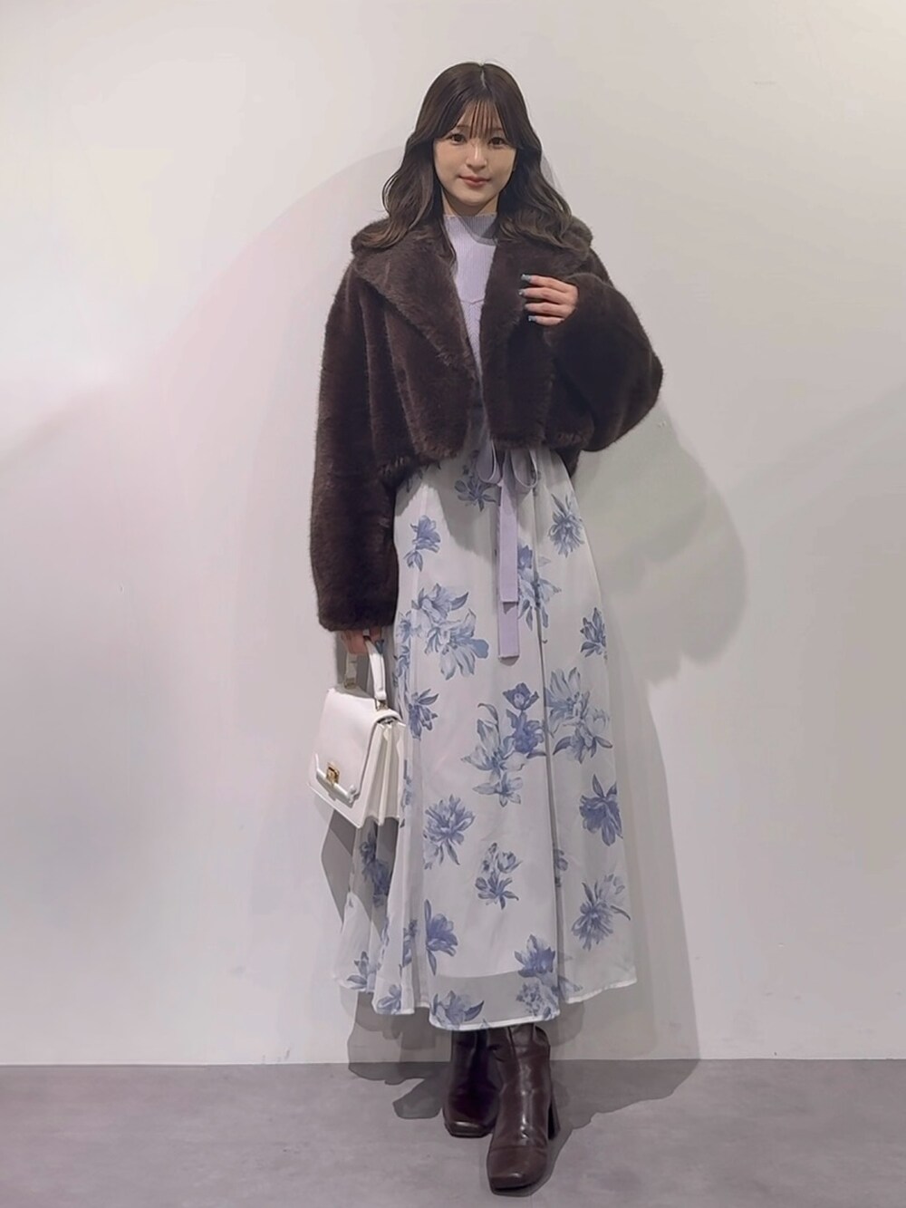 パープル系のワンピース、ブラウン系のブーツ、ホワイト系のハンドバッグを着用したレディースの秋コーディネートの4枚目の写真