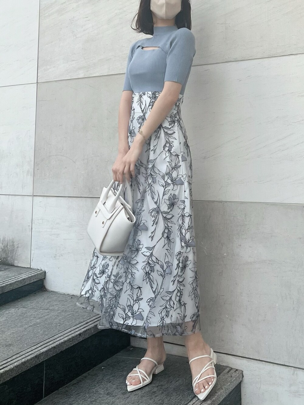 グレー系のスカート、ブルー系のニット/セーター、ホワイト系のトートバッグを着用したレディースの春コーディネートの3枚目の写真