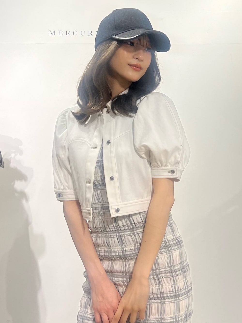 ブラック系のサンダル、ホワイト系のデニムジャケット、ホワイト系のワンピースを着用したレディースの春コーディネートの2枚目の写真