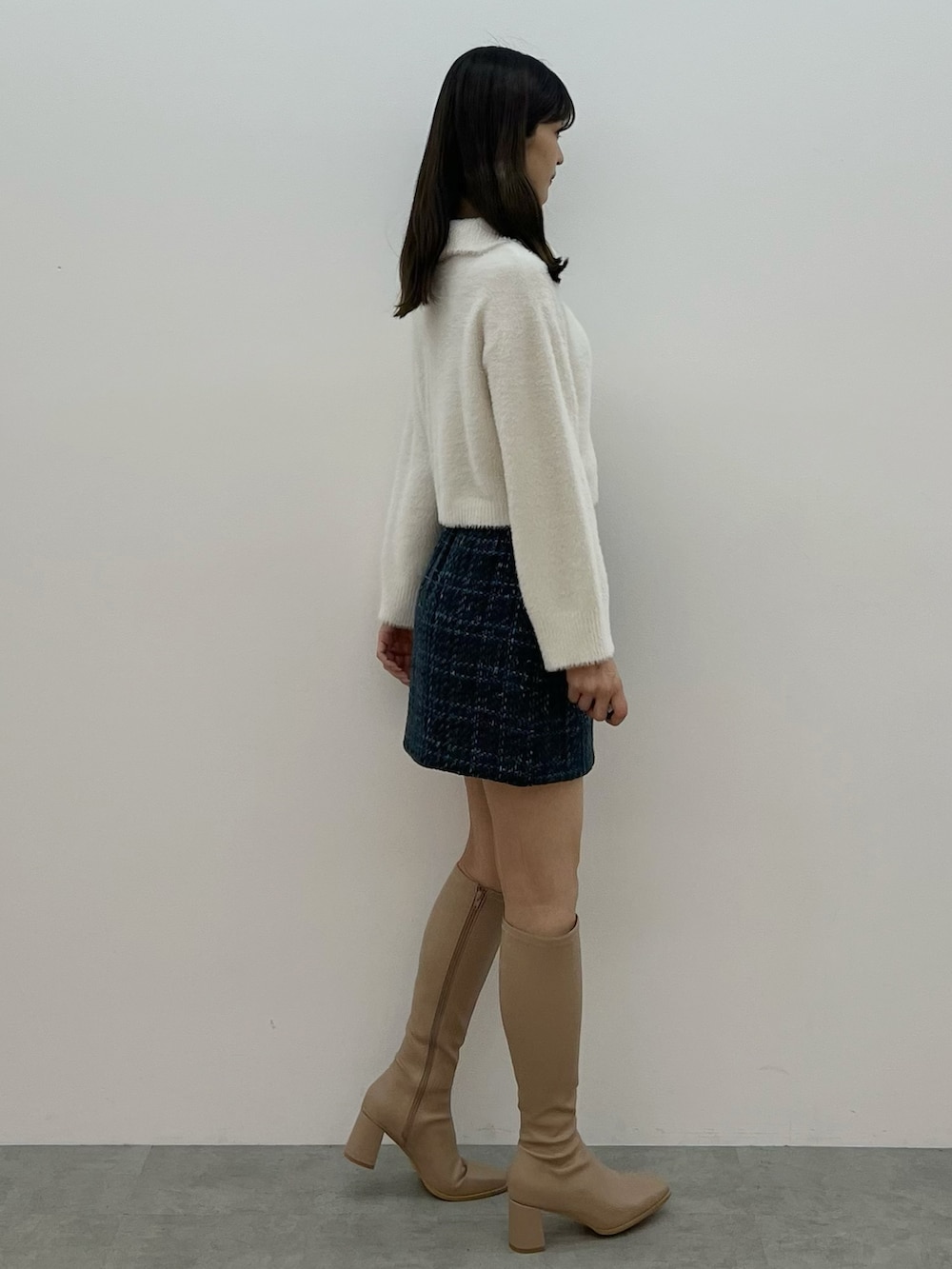 ホワイト系のニット/セーター、ブラック系のスカート、ベージュ系のブーツを着用したレディースの秋コーディネートの6枚目の写真