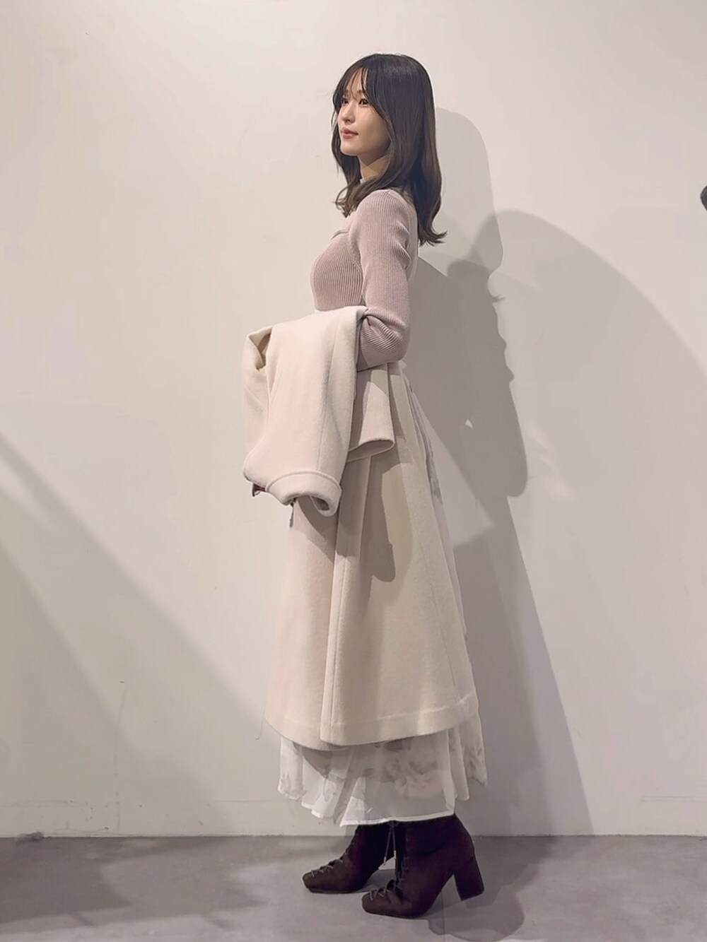 ホワイト系のその他アウター、ピンク系のハンドバッグ、ブラウン系のブーツを着用したレディースの秋コーディネートの6枚目の写真