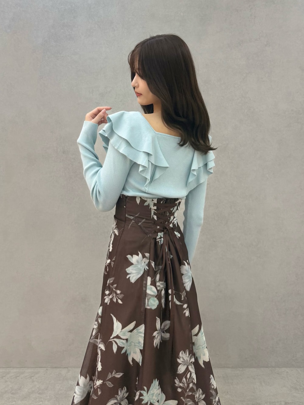 ブラウン系のブーツ、グリーン系のニット/セーター、ブラウン系のスカートを着用したレディースの春コーディネートの2枚目の写真