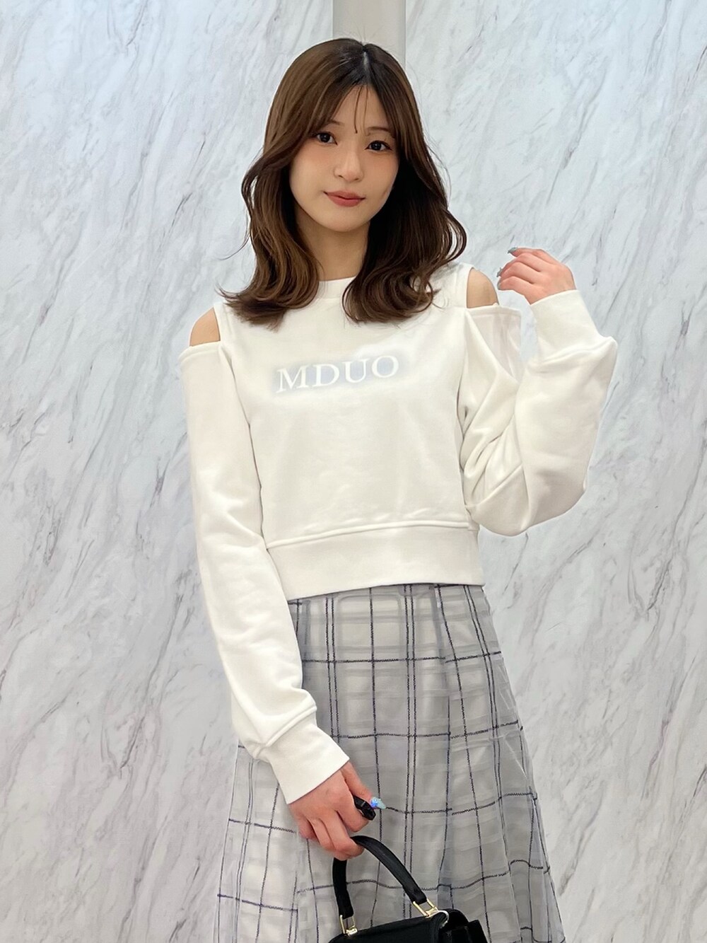 ホワイト系のTシャツ/カットソー、ブルー系のスカート、ブラック系のハンドバッグを着用したレディースの春コーディネートの4枚目の写真
