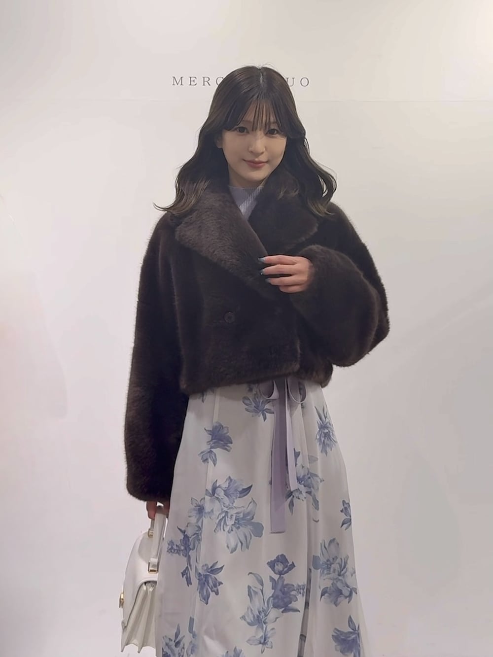 パープル系のワンピース、ブラウン系のブーツ、ホワイト系のハンドバッグを着用したレディースの秋コーディネートの5枚目の写真