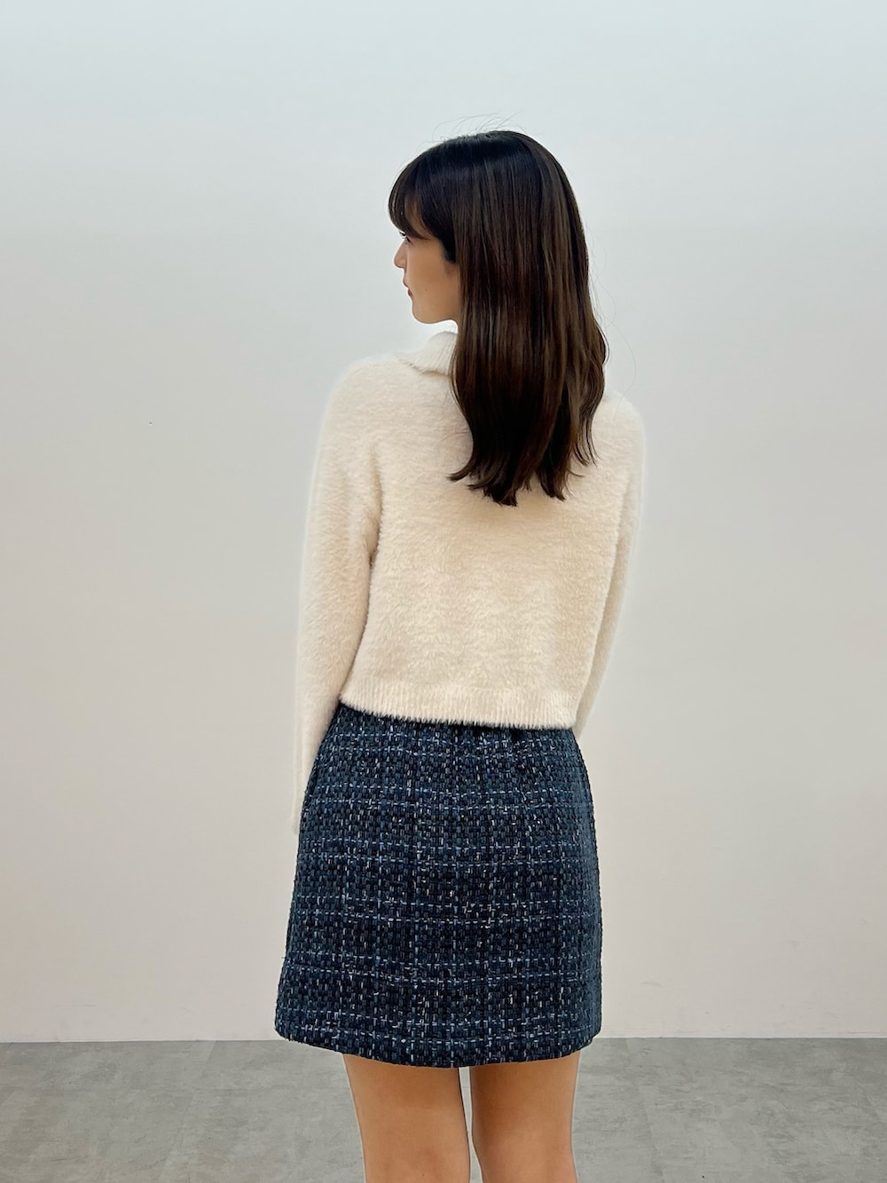 ホワイト系のニット/セーター、ブラック系のスカート、ベージュ系のブーツを着用したレディースの秋コーディネートの5枚目の写真