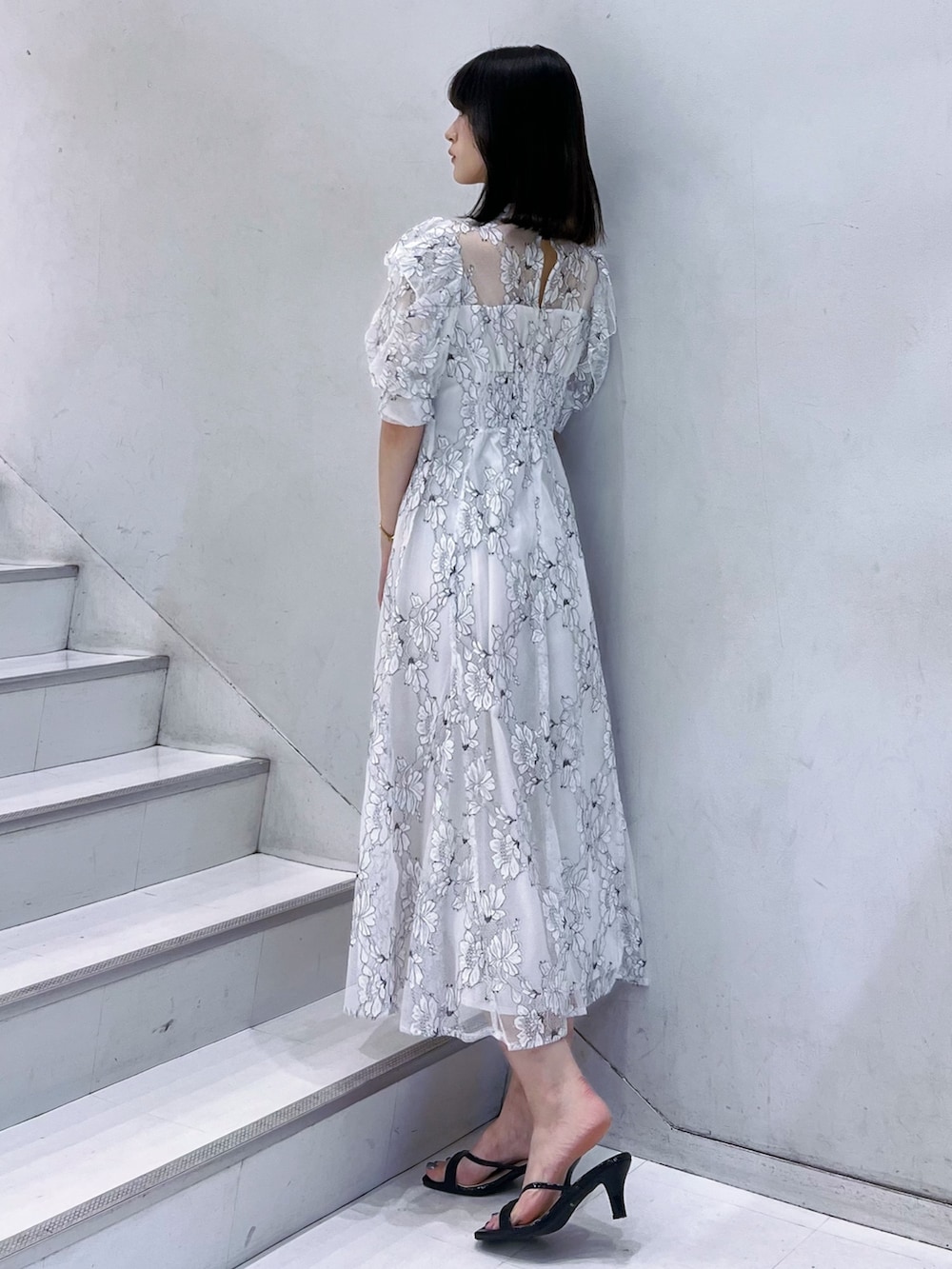 ブラック系のショルダーバッグ、ブラック系のサンダル、ホワイト系のワンピースを着用したレディースの夏コーディネートの3枚目の写真