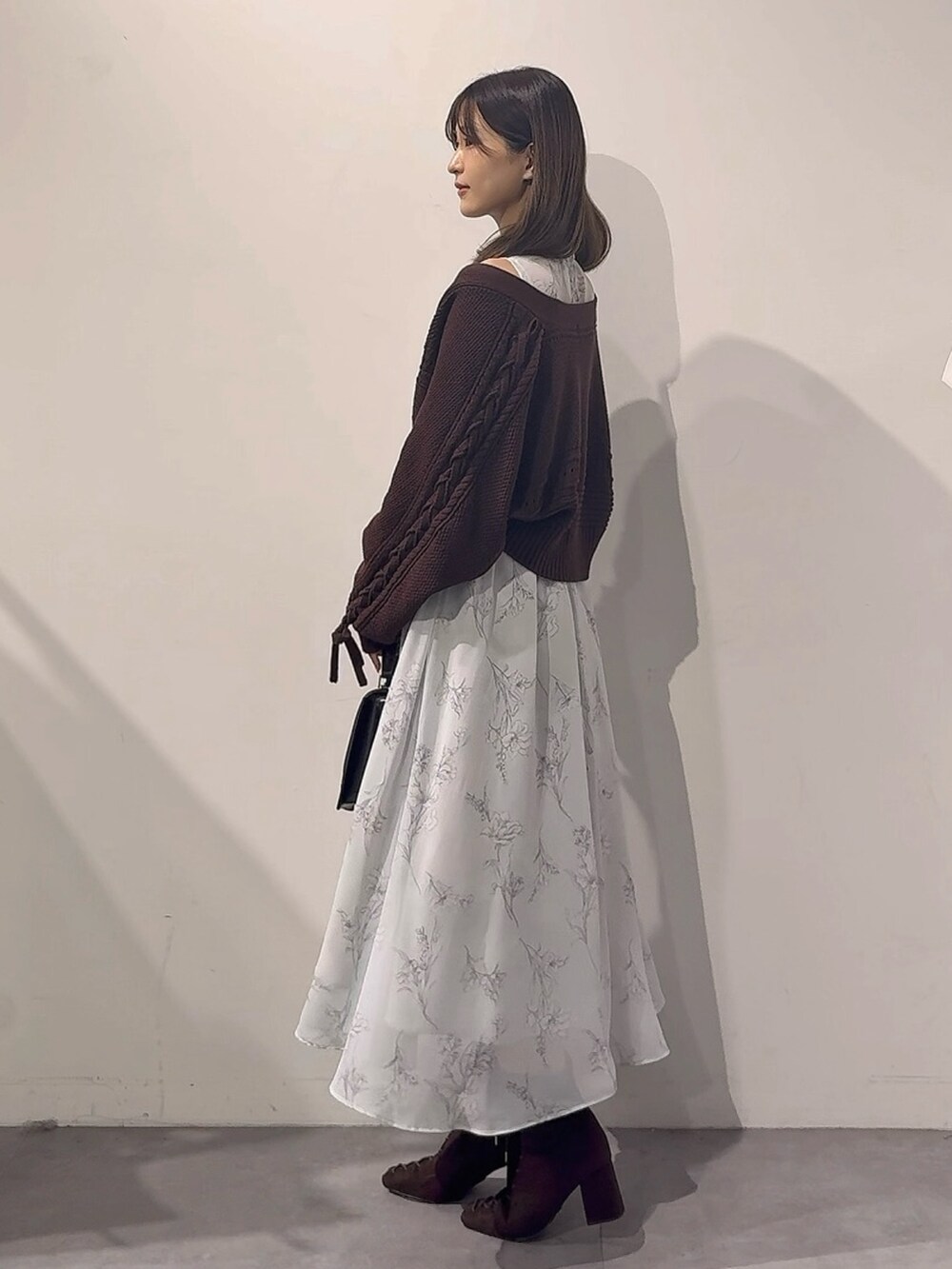 グリーン系のワンピース、ブラウン系のカーディガン/ボレロ、ブラック系のハンドバッグを着用したレディースの秋コーディネートの3枚目の写真