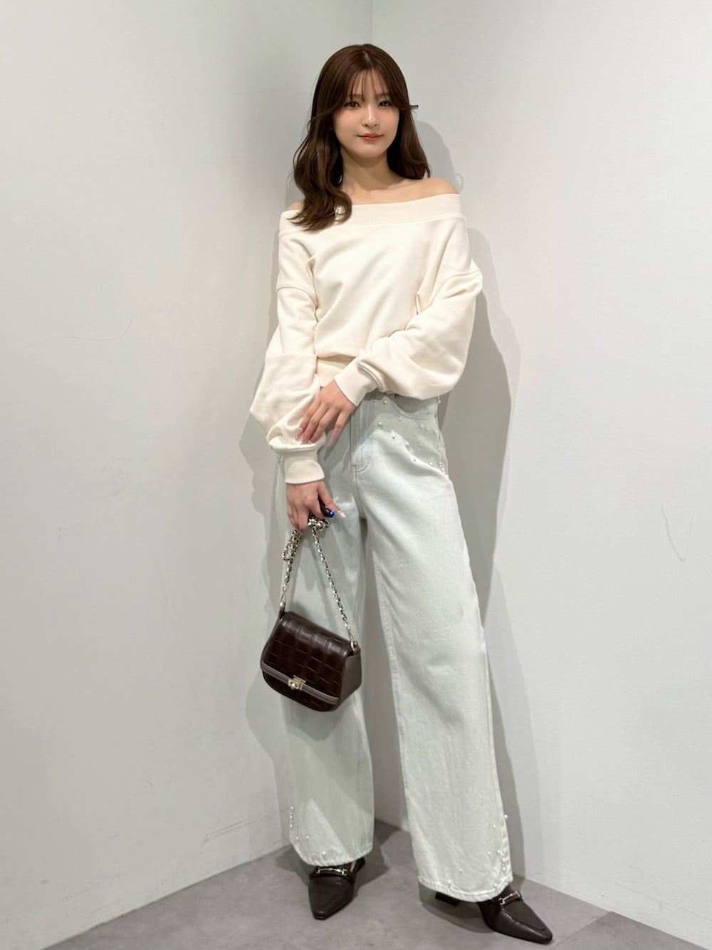 ブラウン系のパンプス、ブルー系のデニムパンツ、ブラウン系のハンドバッグを着用したレディースの春コーディネートの4枚目の写真