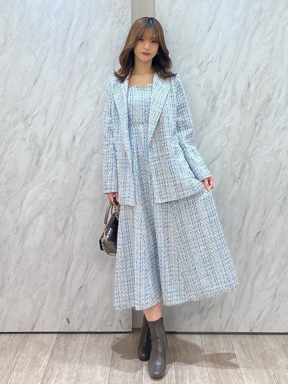 ブルー系のテーラードジャケット、ブルー系のワンピース、ブラウン系のハンドバッグを着用したレディースの冬コーディネートの2枚目の写真