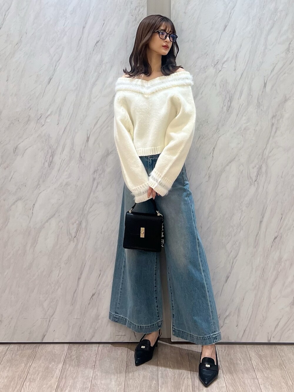 ホワイト系のニット/セーター、ブルー系のデニムパンツ、ブラック系のハンドバッグを着用したレディースの冬コーディネートの6枚目の写真