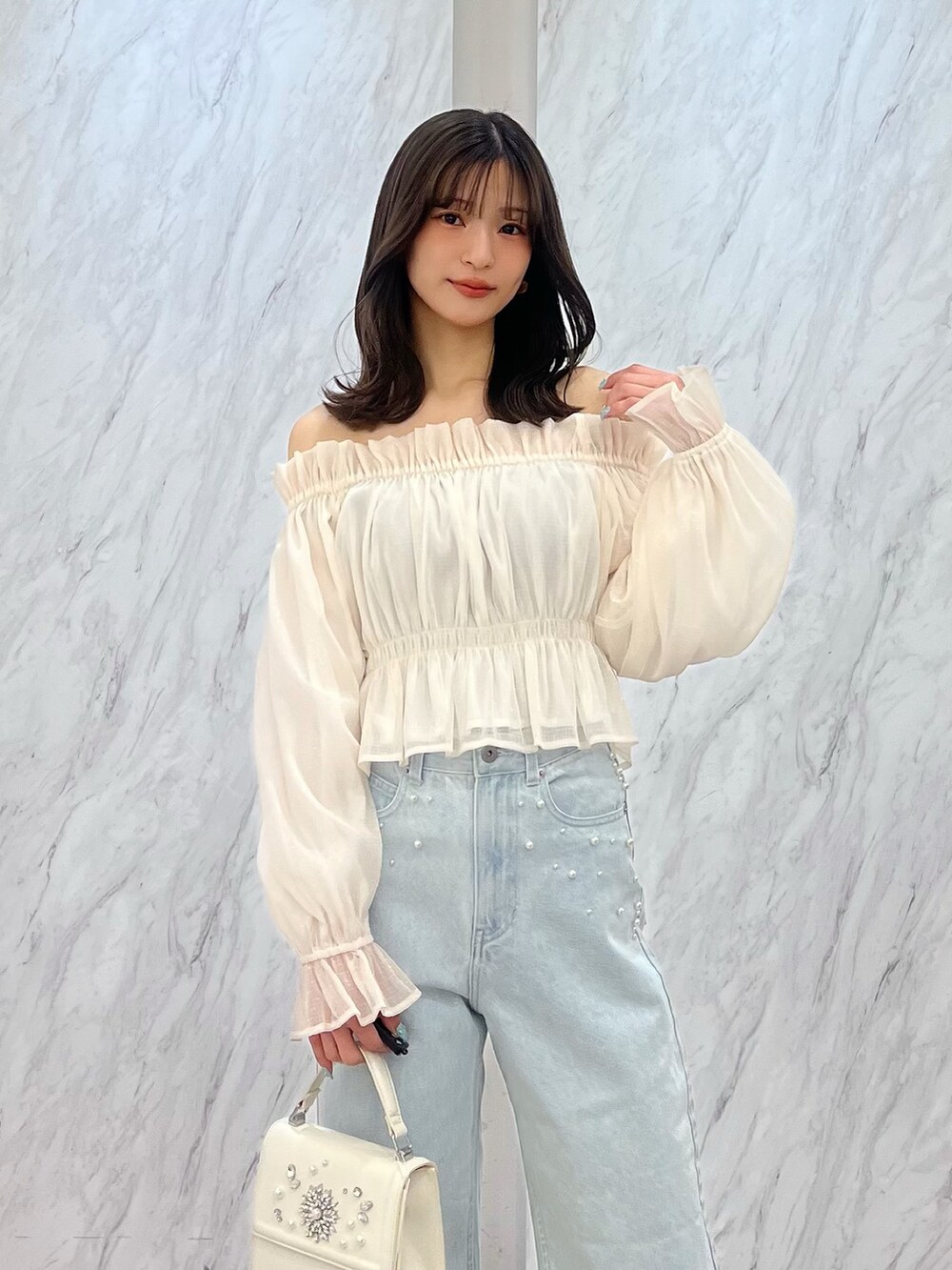 ホワイト系のシャツ/ブラウス、ブルー系のデニムパンツ、ホワイト系のパンプスを着用したレディースの冬コーディネートの3枚目の写真
