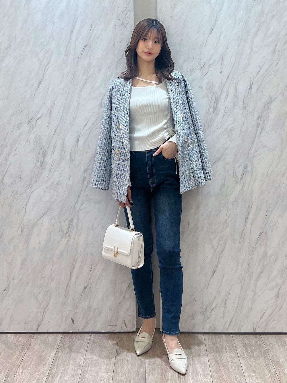 ブルー系のテーラードジャケット、ブルー系のデニムパンツ、ホワイト系のハンドバッグを着用したレディースの冬コーディネートの6枚目の写真