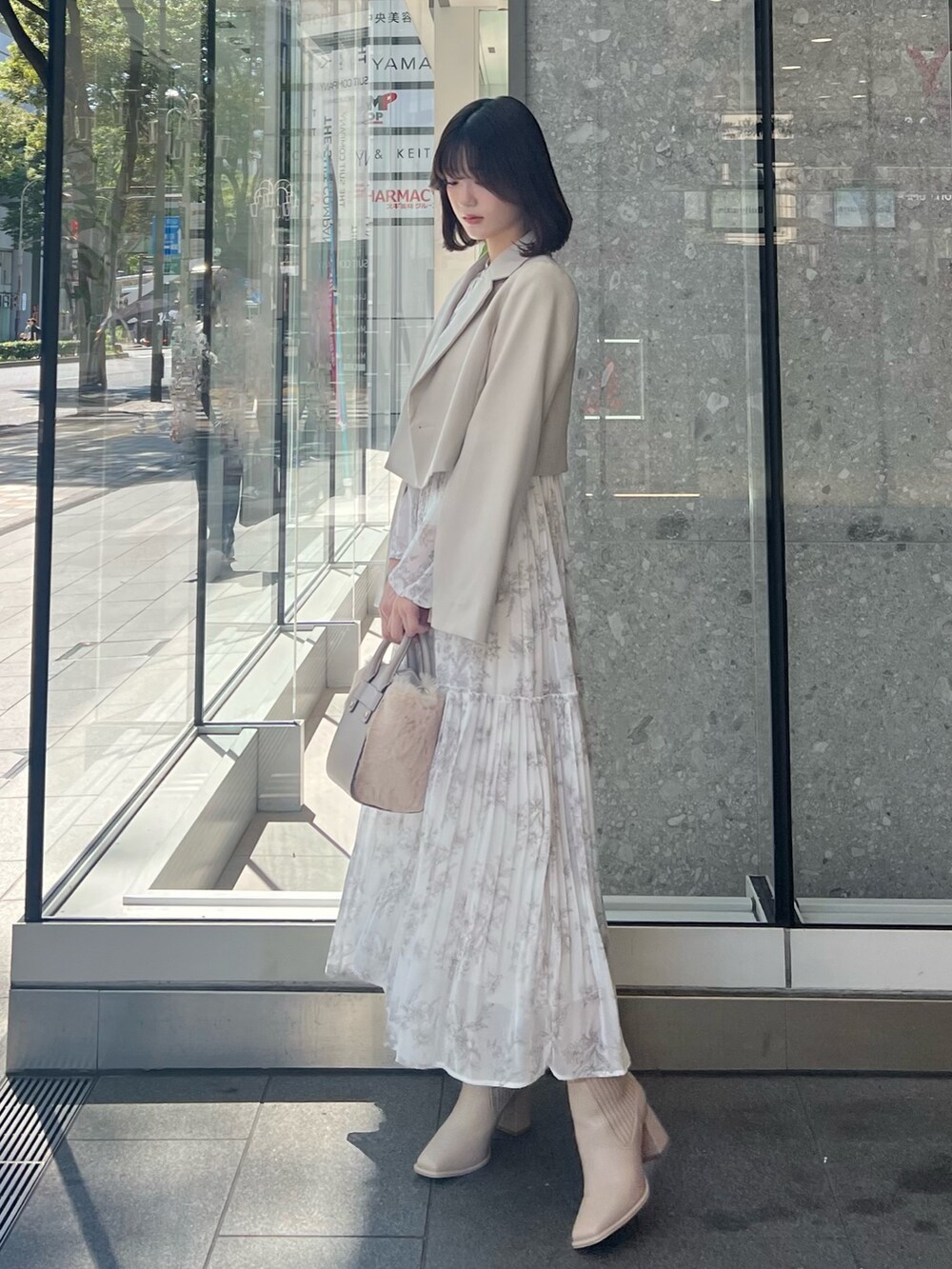 ホワイト系のハンドバッグ、ベージュ系のテーラードジャケット、ベージュ系のブーツを着用したレディースの秋コーディネートの4枚目の写真