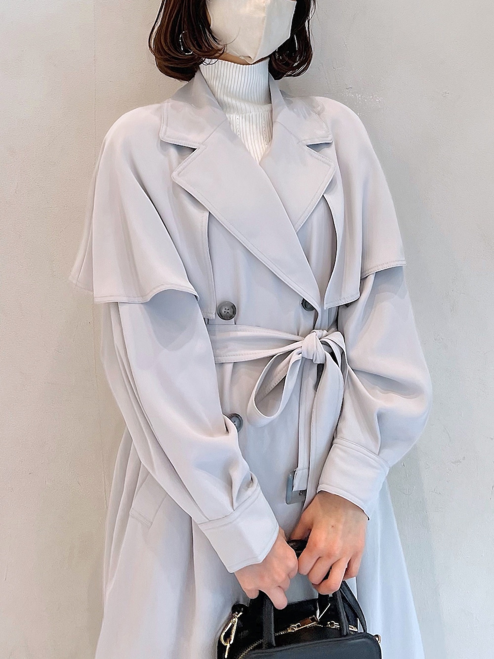 グレー系のトレンチコート、ブラック系のブーツ、ブラック系のハンドバッグを着用したレディースの冬コーディネートの5枚目の写真