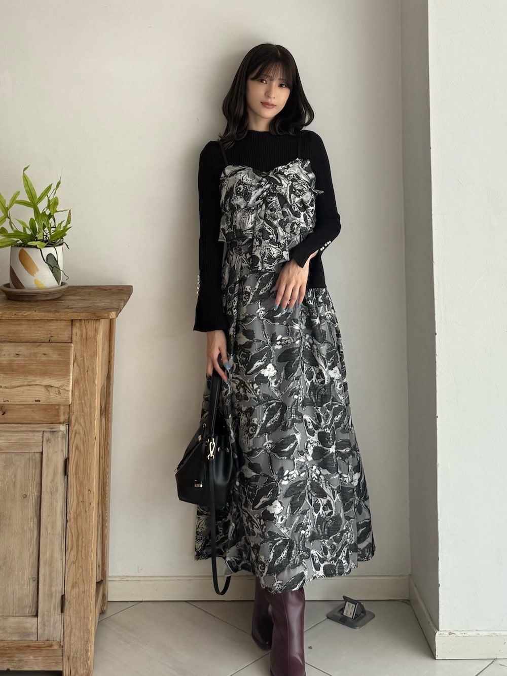 ブラック系のニット/セーター、ブラック系のワンピース、レッド系のブーツを着用したレディースの秋コーディネートの7枚目の写真