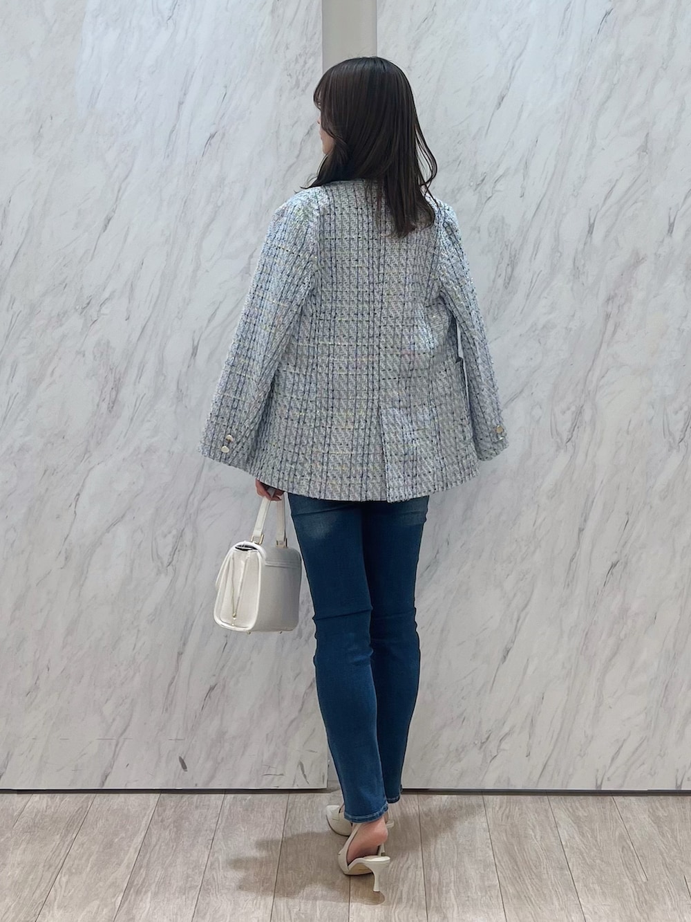 ブルー系のテーラードジャケット、ブルー系のデニムパンツ、ホワイト系のハンドバッグを着用したレディースの冬コーディネートの3枚目の写真