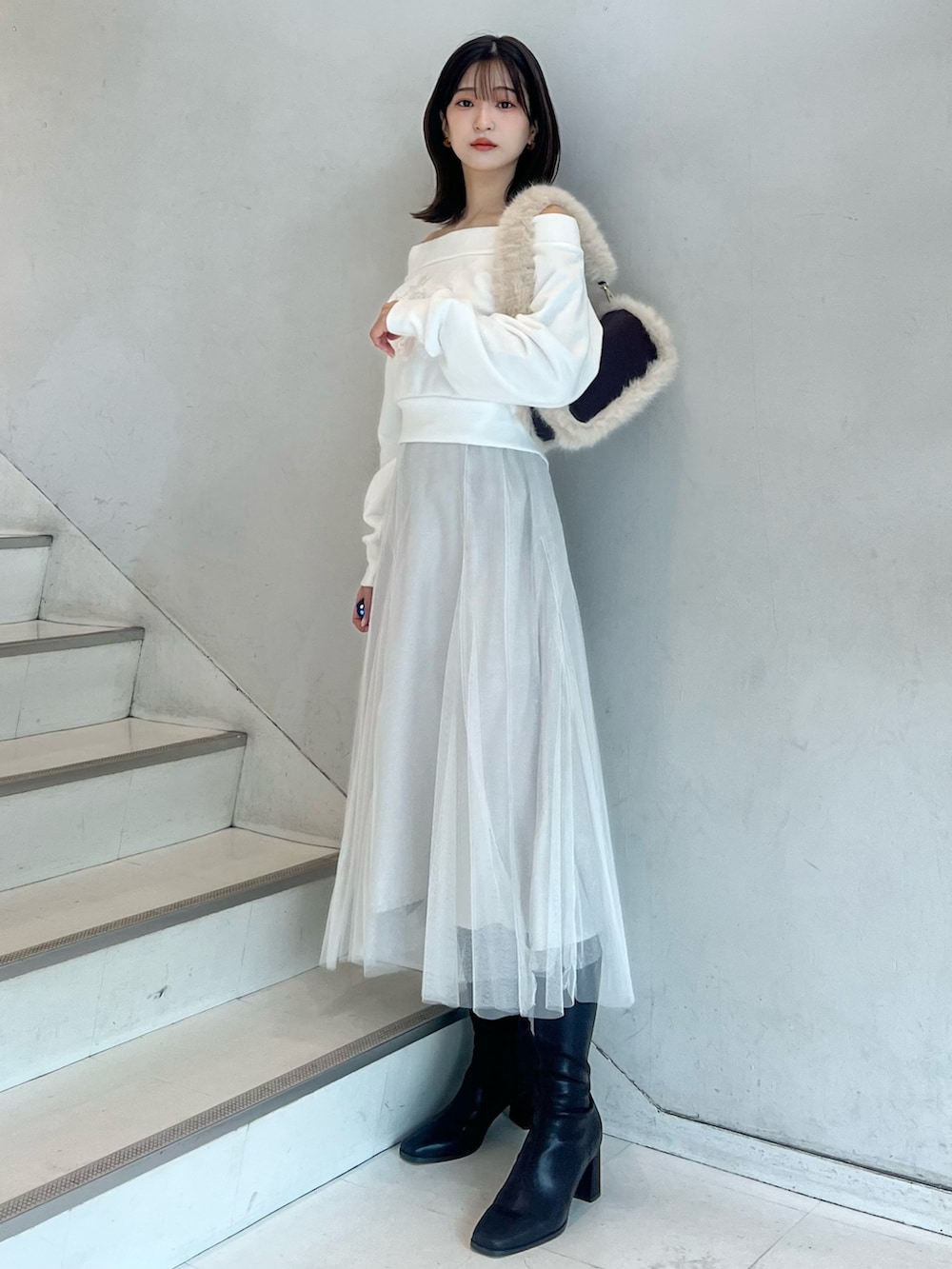 ブラウン系のショルダーバッグ、ホワイト系のスカート、ブラウン系のブーツを着用したレディースの秋コーディネートの2枚目の写真