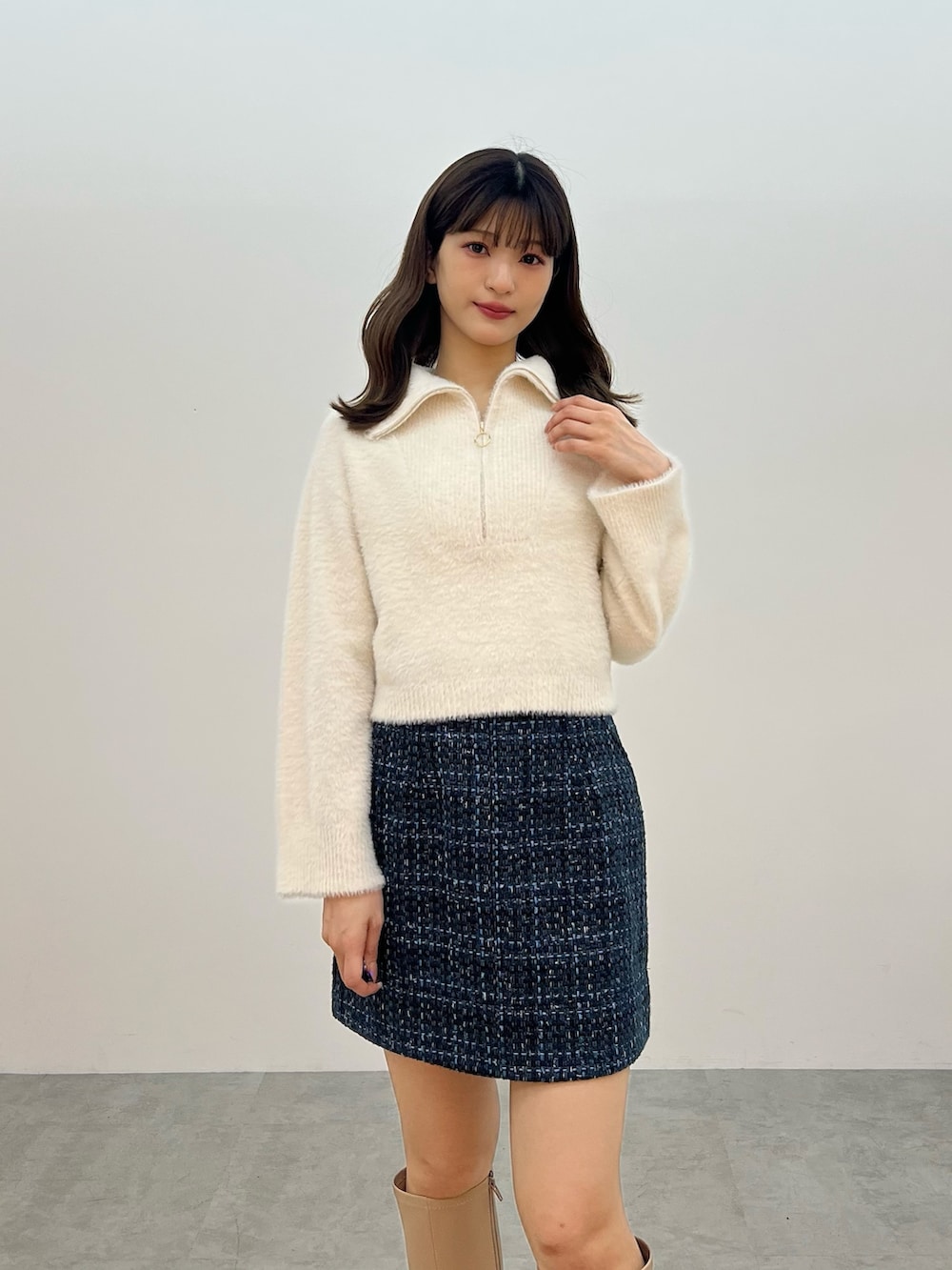 ホワイト系のニット/セーター、ブラック系のスカート、ベージュ系のブーツを着用したレディースの秋コーディネートの4枚目の写真