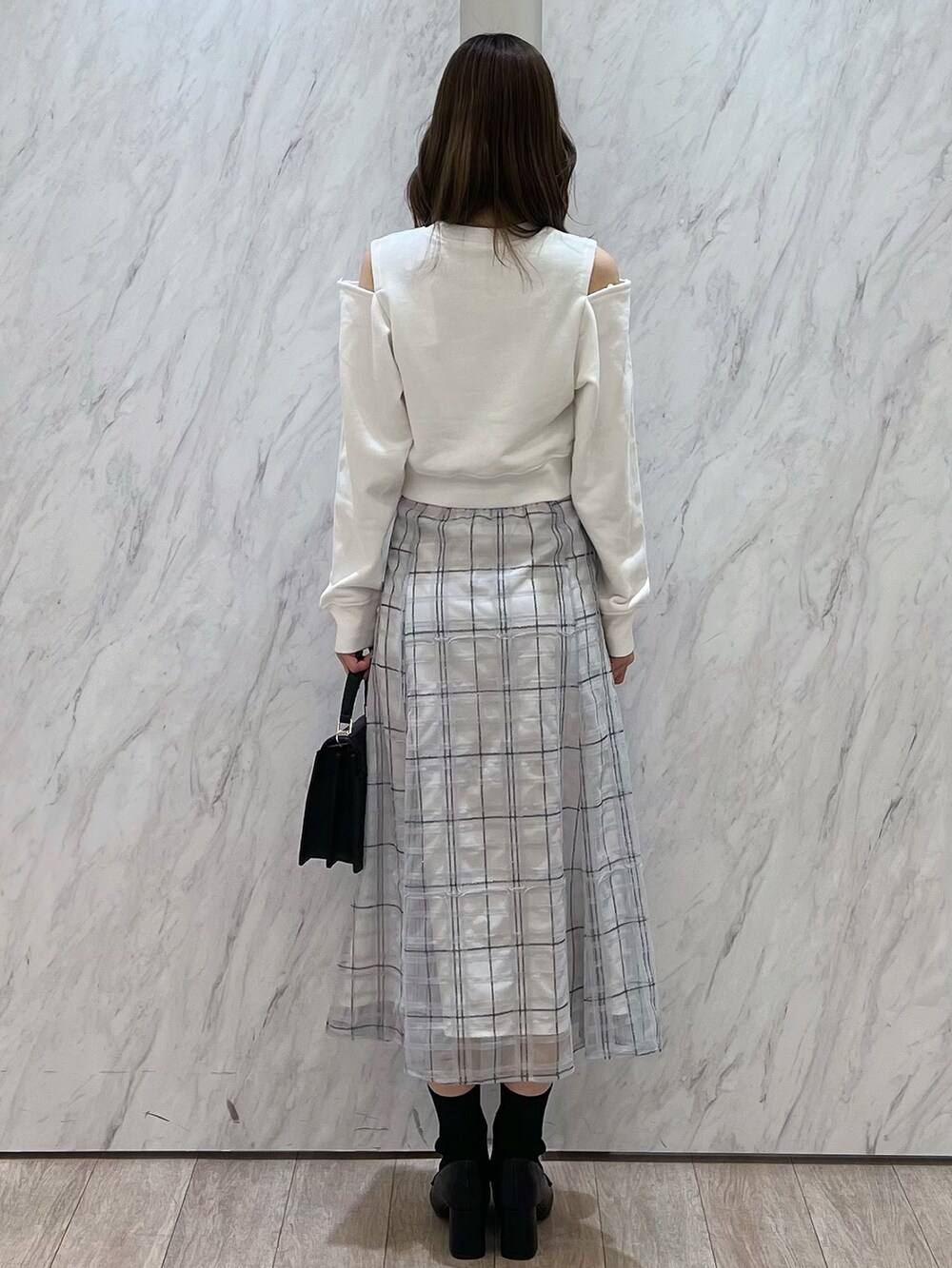 ホワイト系のTシャツ/カットソー、ブルー系のスカート、ブラック系のハンドバッグを着用したレディースの春コーディネートの3枚目の写真