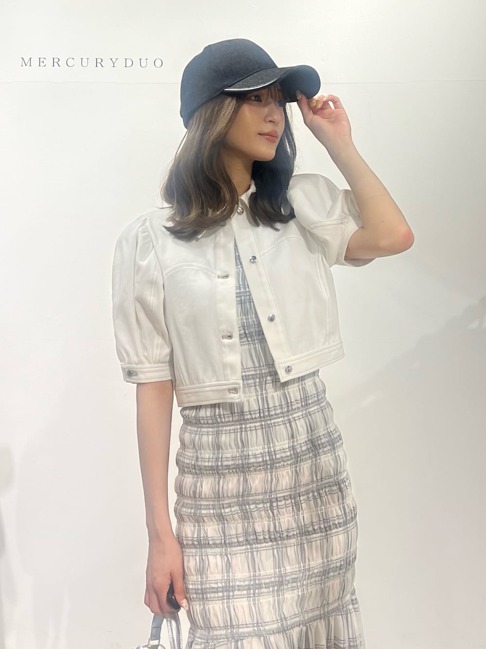 ブラック系のサンダル、ホワイト系のデニムジャケット、ホワイト系のワンピースを着用したレディースの春コーディネートの3枚目の写真