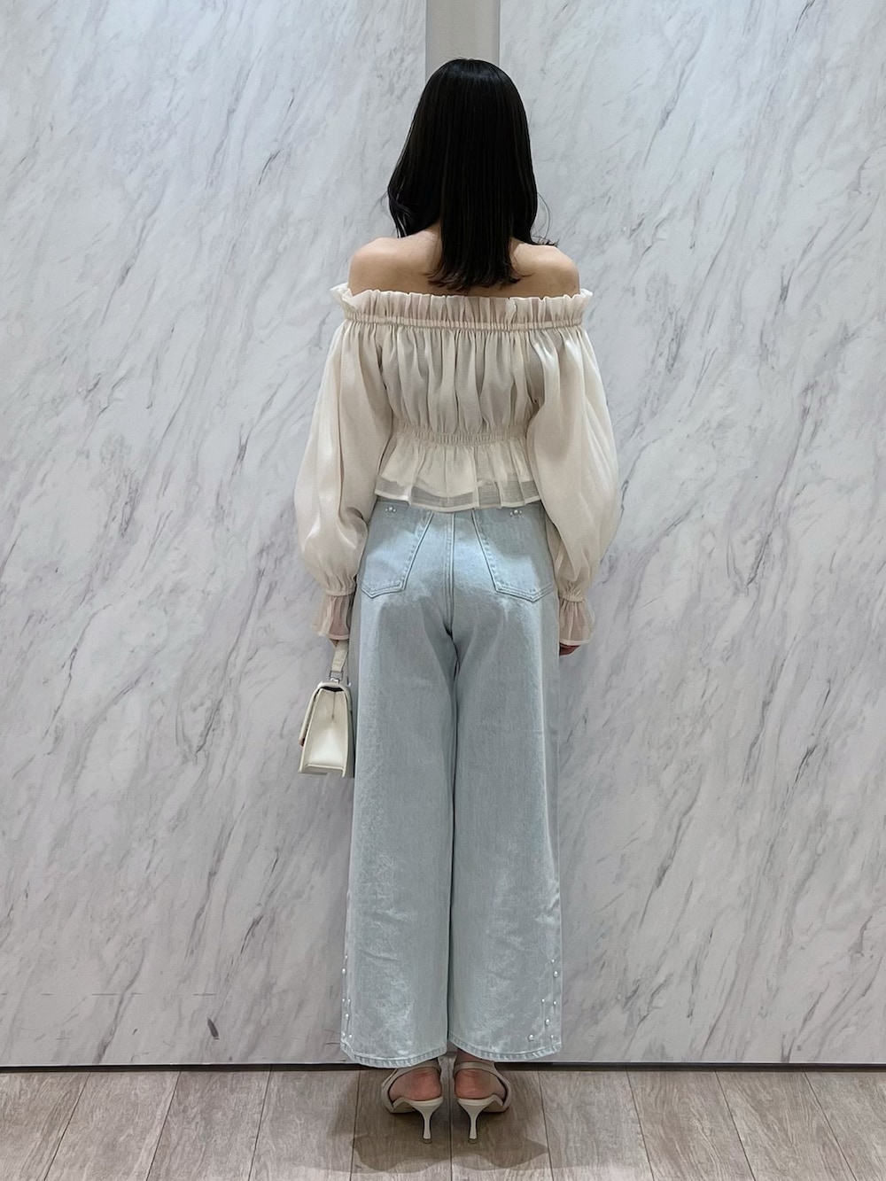 ホワイト系のシャツ/ブラウス、ブルー系のデニムパンツ、ホワイト系のパンプスを着用したレディースの冬コーディネートの6枚目の写真
