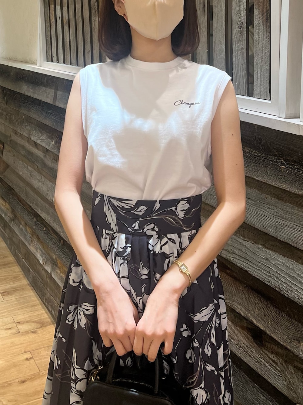 パープル系のスカート、ブラック系のハンドバッグ、ブラック系のサンダルを着用したレディースの春コーディネートの2枚目の写真