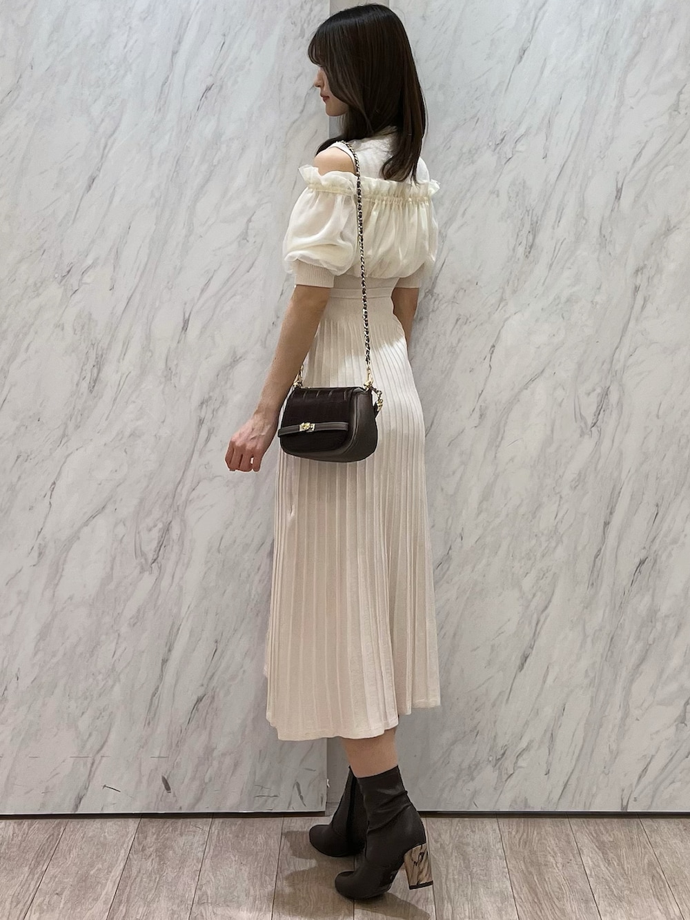 ホワイト系のワンピース、ブラウン系のブーツ、ブラウン系のハンドバッグを着用したレディースの春コーディネートの3枚目の写真