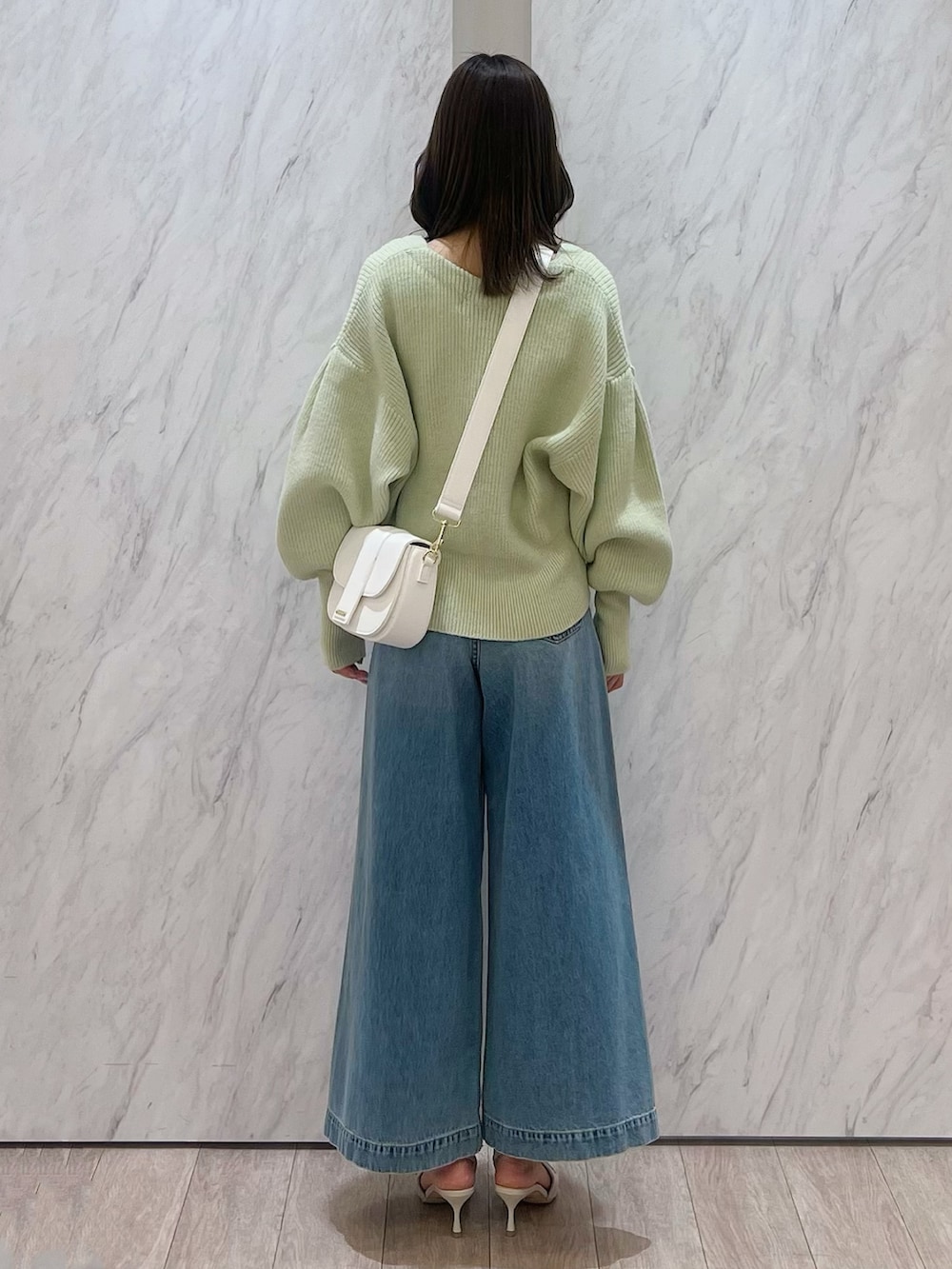 グリーン系のカーディガン/ボレロ、ホワイト系のショルダーバッグ、ブルー系のデニムパンツを着用したレディースの冬コーディネートの7枚目の写真