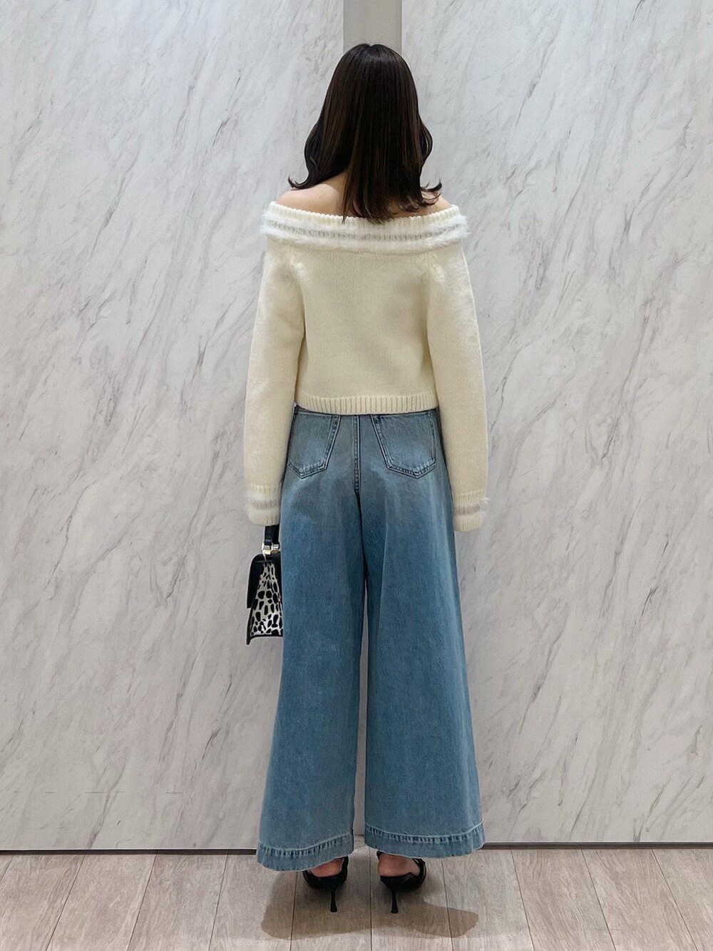 ホワイト系のニット/セーター、ブルー系のデニムパンツ、ブラック系のハンドバッグを着用したレディースの冬コーディネートの4枚目の写真