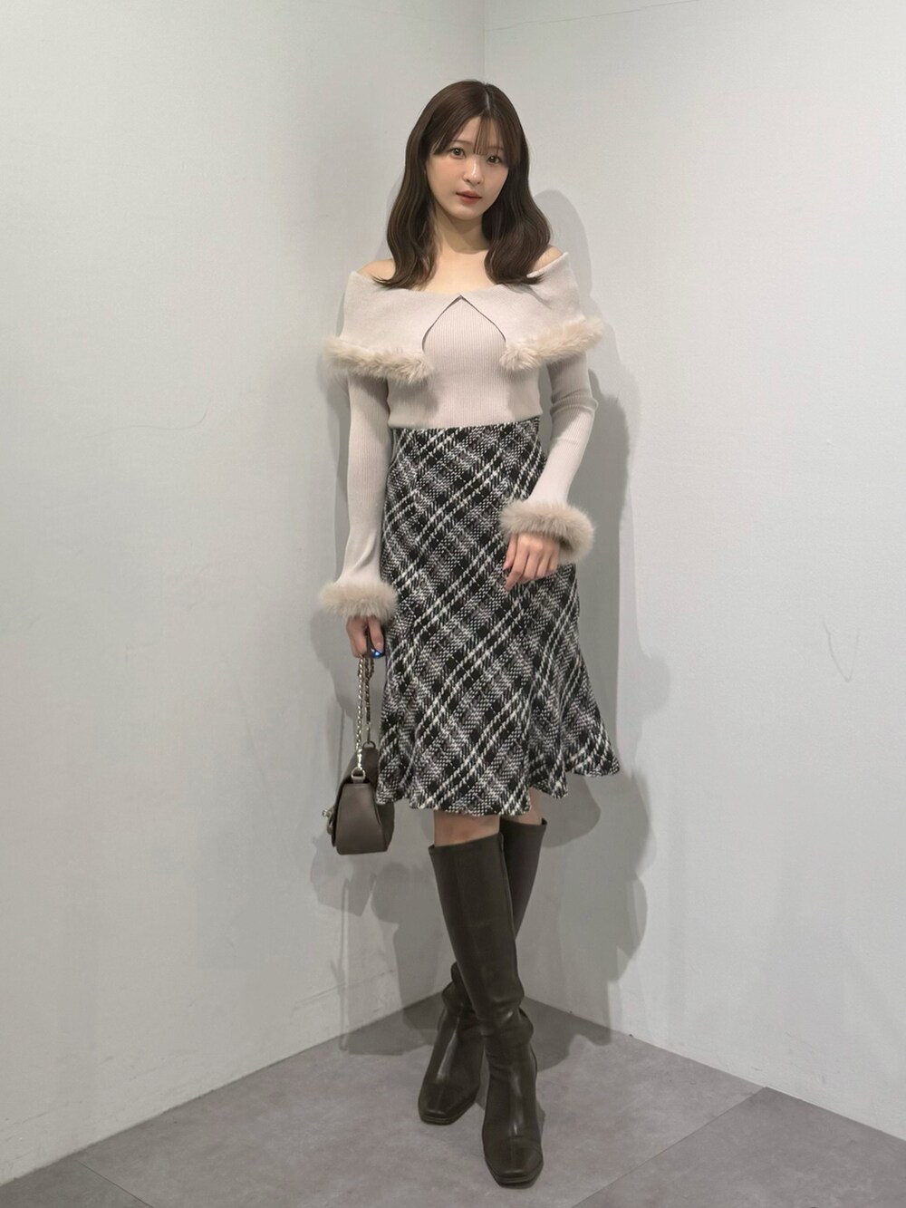 ベージュ系のニット/セーター、ブラック系のスカート、ブラウン系のブーツを着用したレディースの冬コーディネートの5枚目の写真