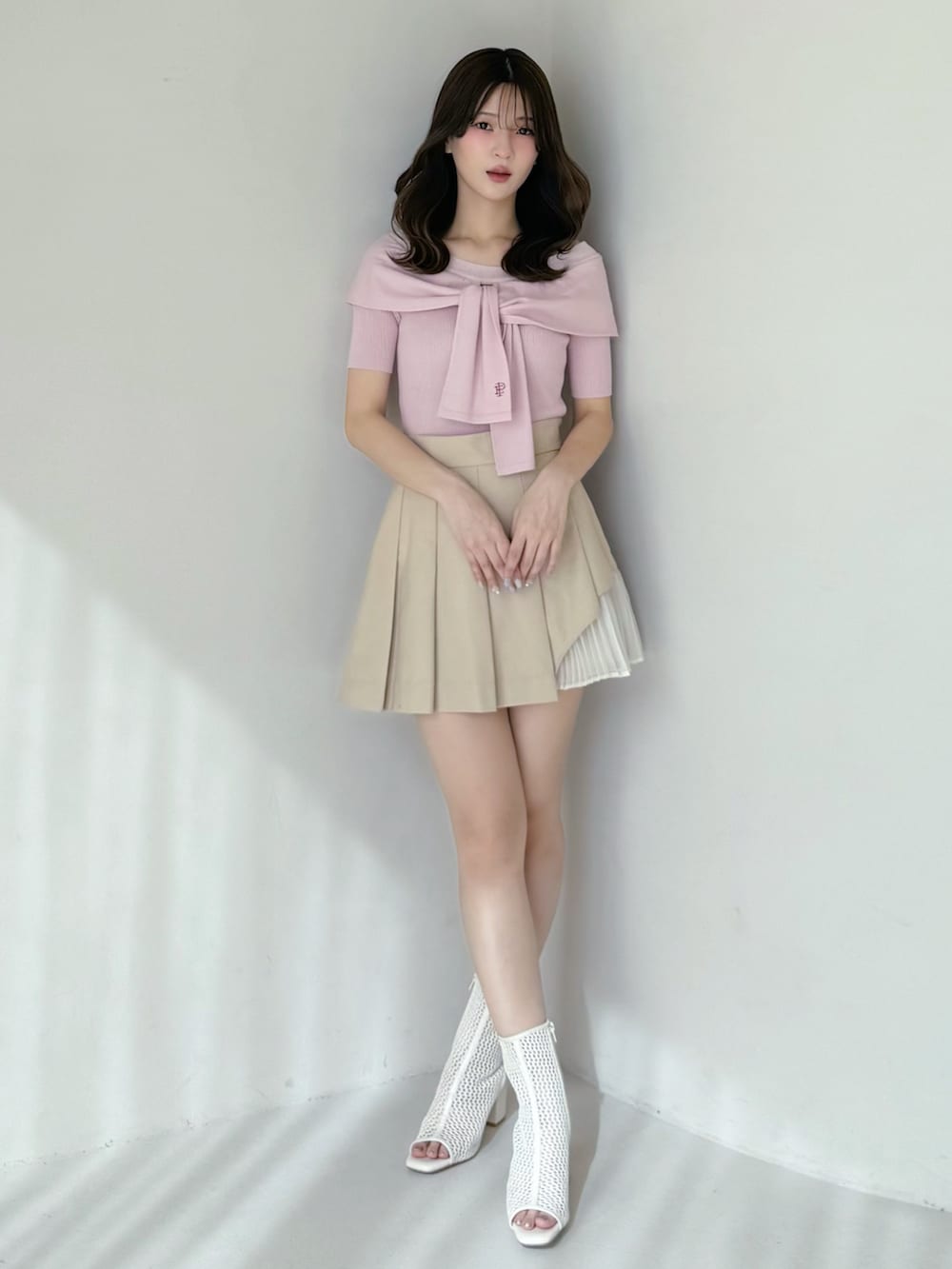 ベージュ系のスカート、ピンク系のニット/セーター、ホワイト系のブーツを着用したレディースの春コーディネートの4枚目の写真