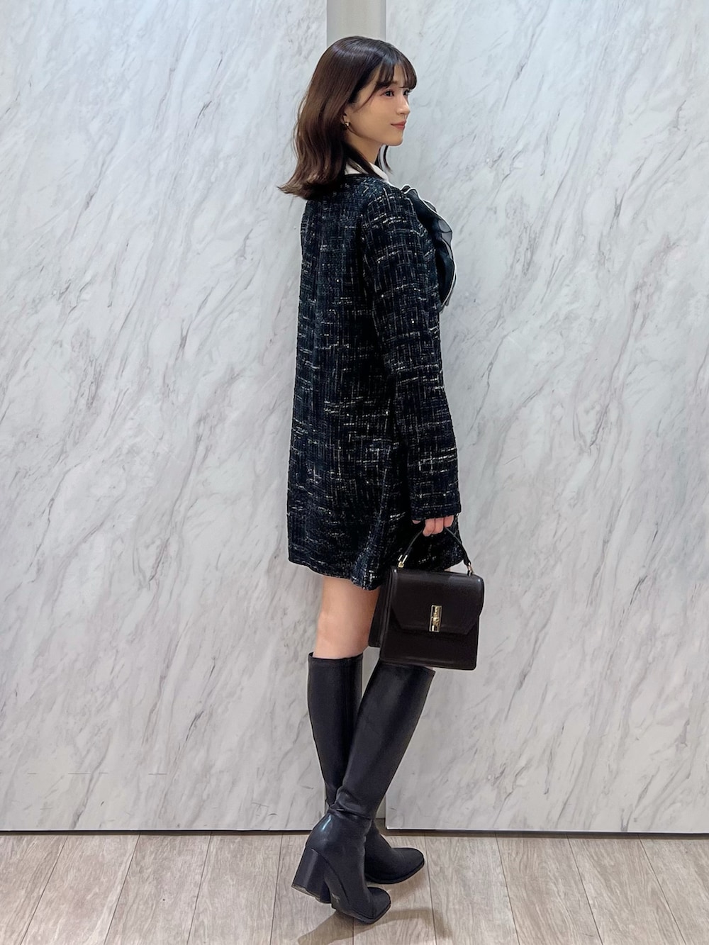 ブラック系のワンピース、ブラウン系のハンドバッグ、ブラウン系のブーツを着用したレディースの秋コーディネートの3枚目の写真