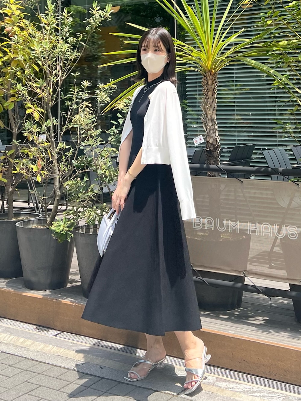 ブラック系のワンピース、ホワイト系のカーディガン/ボレロ、ブルー系のハンドバッグを着用したレディースの春コーディネートの7枚目の写真