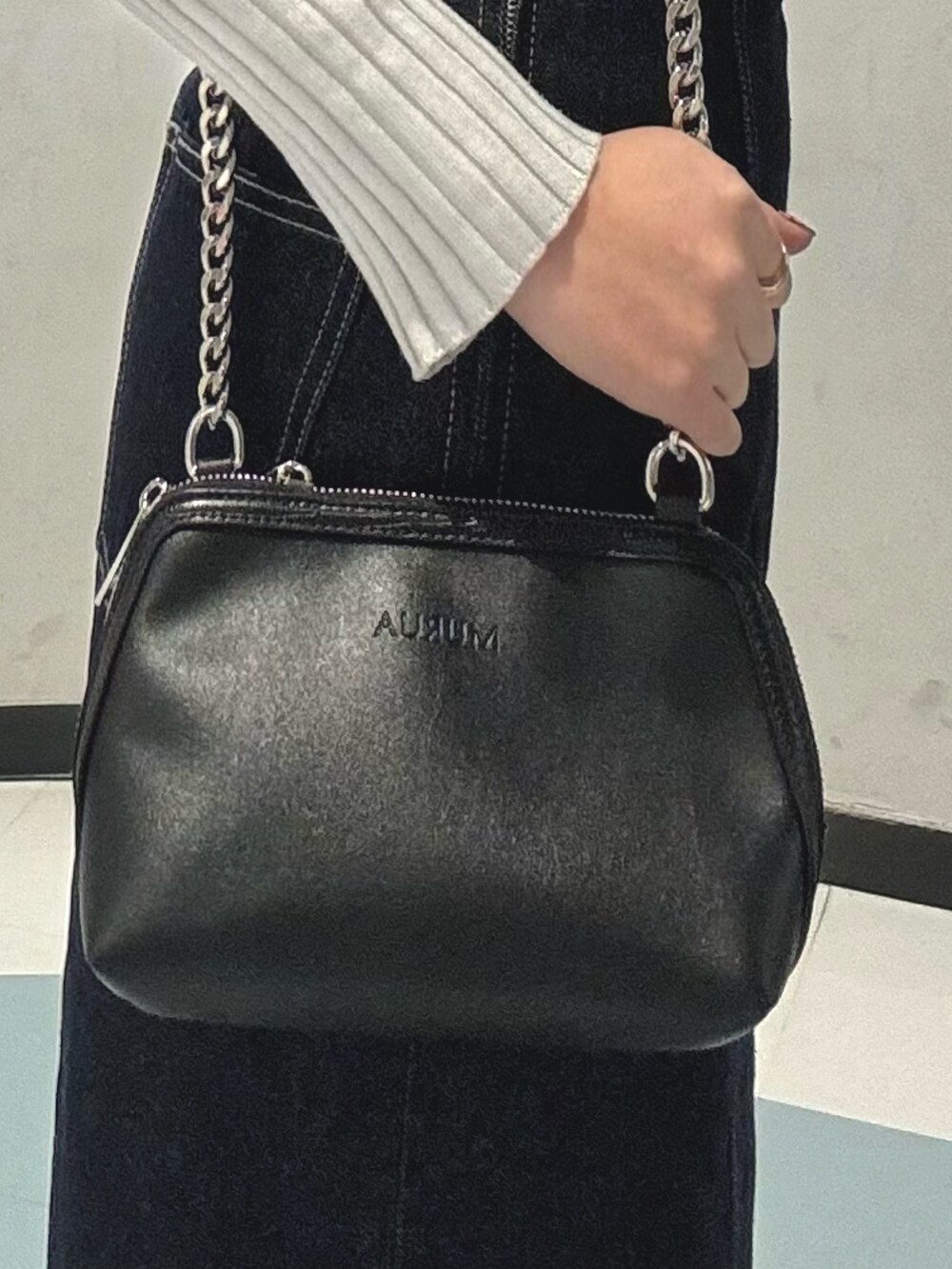 ブラック系のハンドバッグ、ブルー系のデニムジャケット、ブルー系のワンピースを着用したレディースの冬コーディネートの5枚目の写真