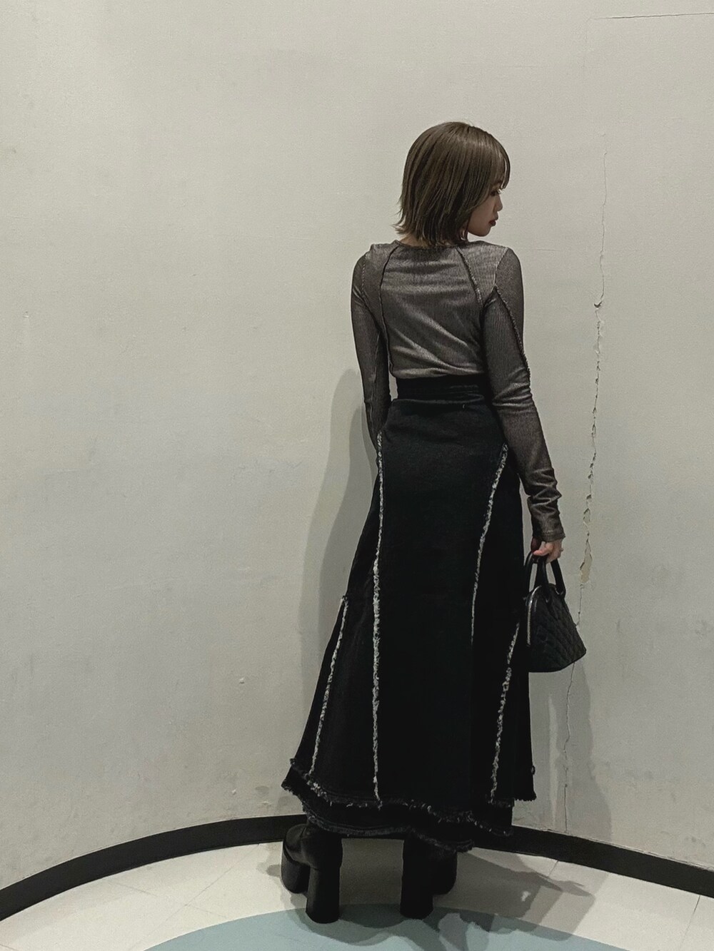 ブラック系のデニムスカート、グレー系のTシャツ/カットソー、ブラック系のハンドバッグを着用したレディースの冬コーディネートの3枚目の写真