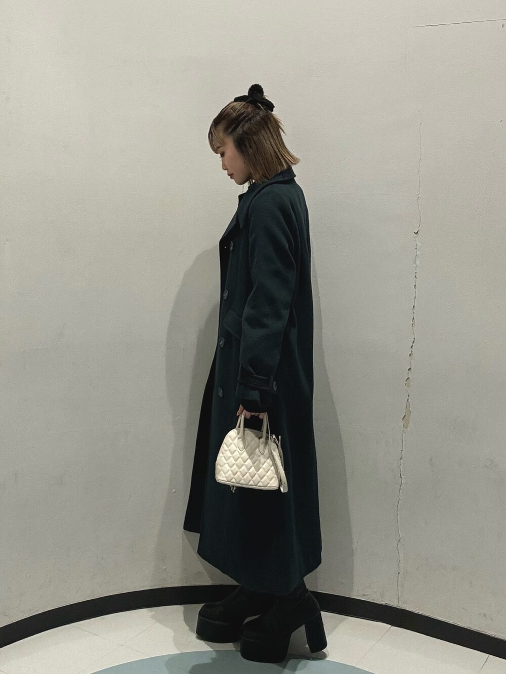ホワイト系のハンドバッグ、ブラック系のワンピース、グリーン系のチェスターコートを着用したレディースの冬コーディネートの2枚目の写真