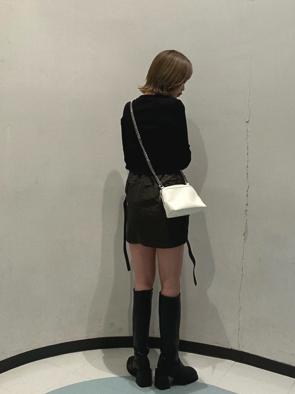 ブラック系のブーツ、ブラック系のTシャツ/カットソー、ベージュ系のスカートを着用したレディースの冬コーディネートの3枚目の写真