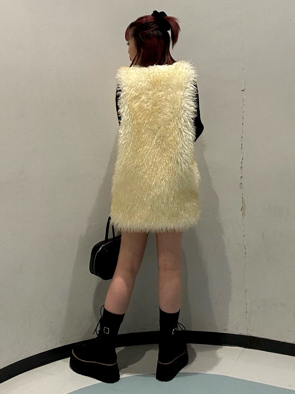 ブラック系のニット/セーター、ホワイト系のベスト、グリーン系のスカートを着用したレディースの秋コーディネートの3枚目の写真