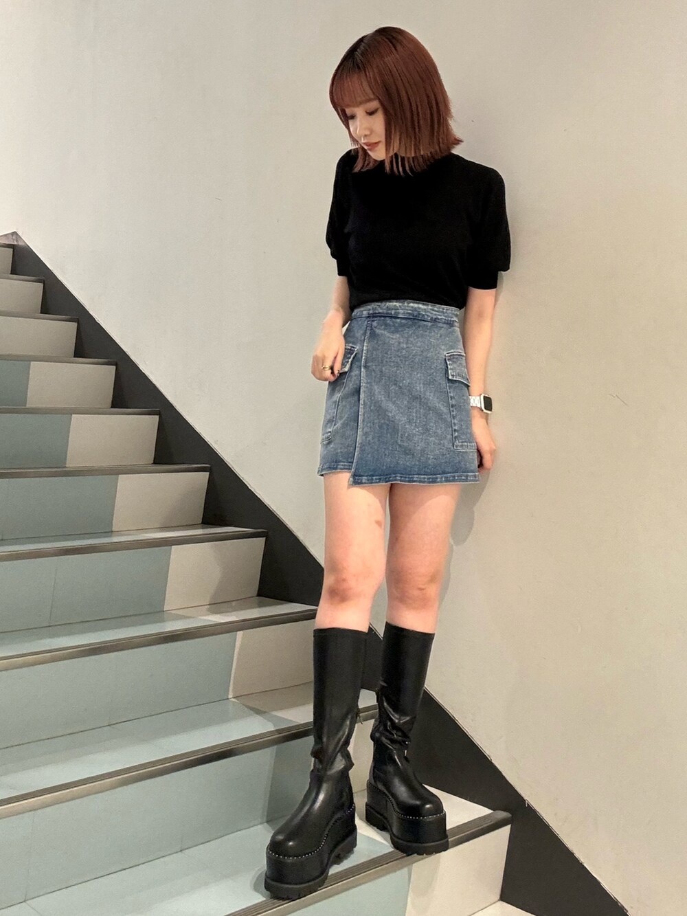 ブラック系のニット/セーター、ブルー系のスカート、ブラック系のブーツを着用したレディースの夏コーディネートの5枚目の写真