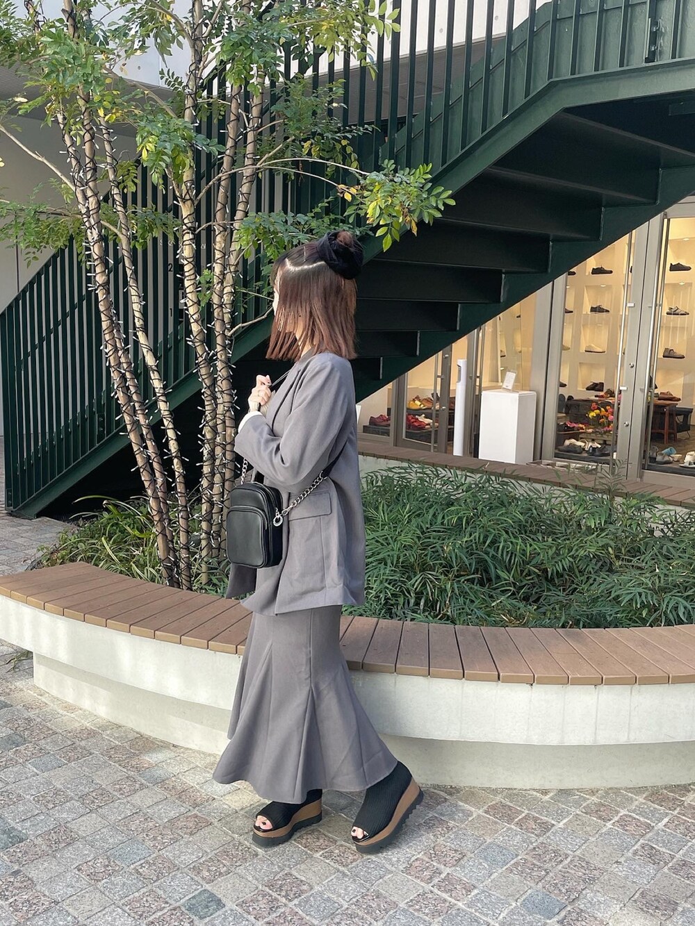 ブラック系のショルダーバッグ、グレー系のテーラードジャケット、グレー系のスカートを着用したレディースの冬コーディネートの3枚目の写真