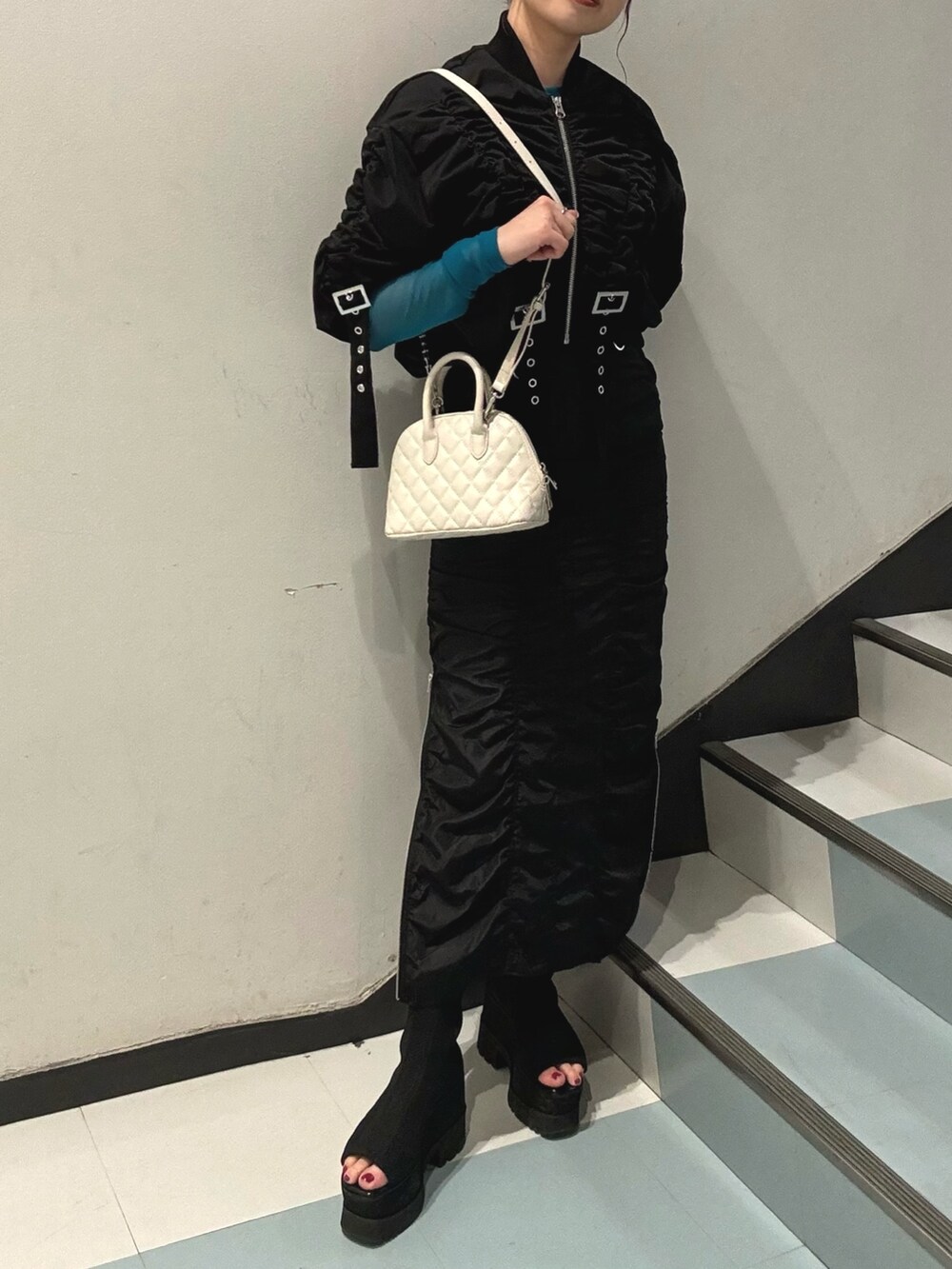 ブラック系のスカート、ホワイト系のハンドバッグ、ブラック系のブルゾンを着用したレディースの春コーディネートの7枚目の写真