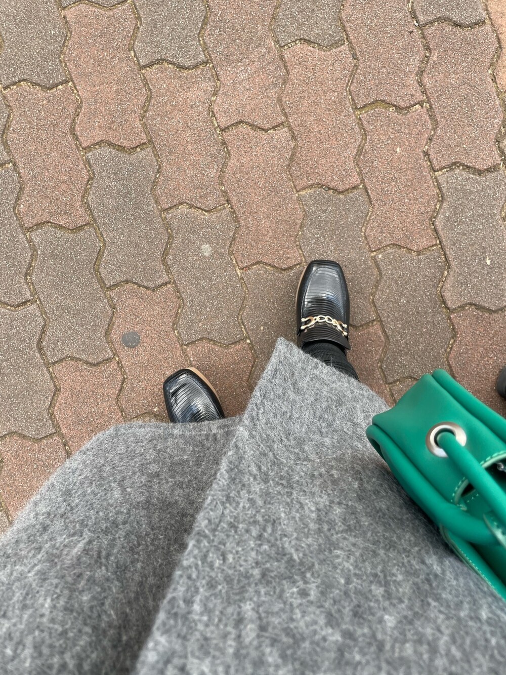 グレー系のチェスターコート、ブラック系のワンピース、ブラック系のローファーを着用したレディースの冬コーディネートの5枚目の写真