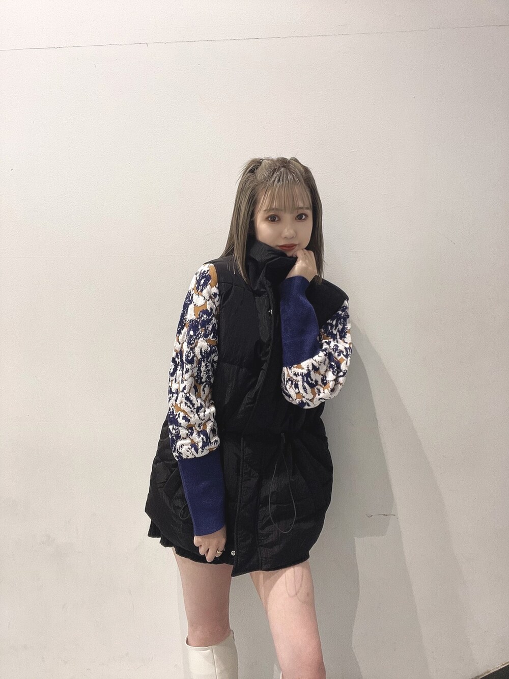 グリーン系のハンドバッグ、ブラック系のダウンベスト、ホワイト系のブーツを着用したレディースの秋コーディネートの2枚目の写真