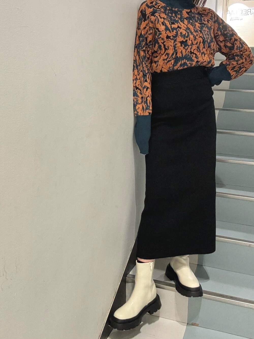 ブラック系のスカート、グリーン系のニット/セーター、ブラック系のハンドバッグを着用したレディースの冬コーディネートの5枚目の写真