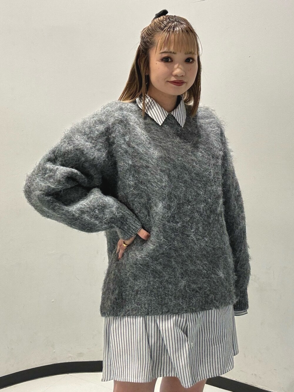 ブラック系のハンドバッグ、グレー系のニット/セーター、ブラック系のブーツを着用したレディースの秋コーディネートの2枚目の写真