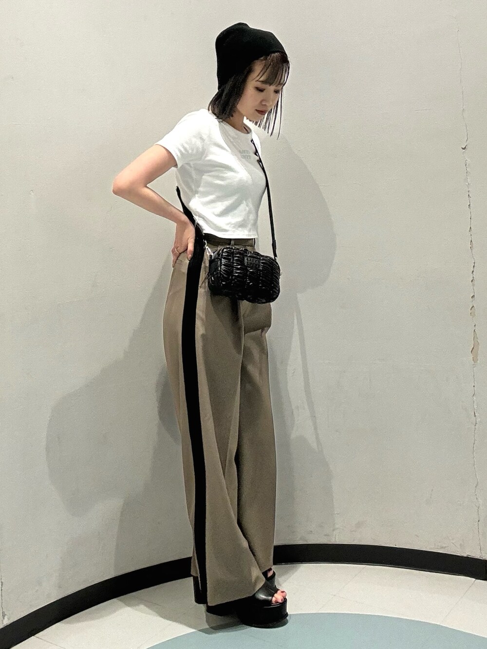 ブラック系のショルダーバッグ、ブラック系のサンダル、ホワイト系のTシャツ/カットソーを着用したレディースの春コーディネートの2枚目の写真