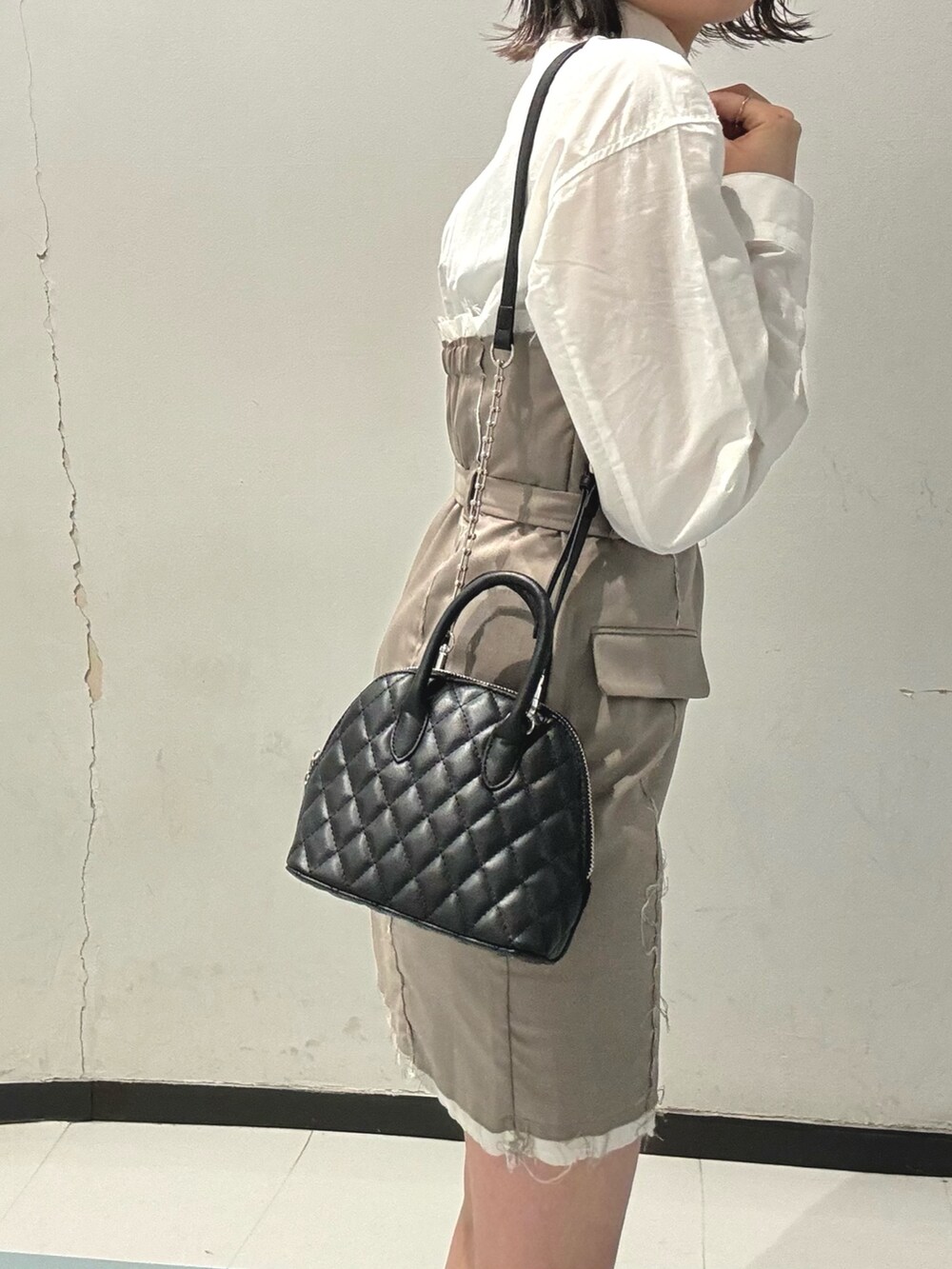 ベージュ系のワンピース、ブラック系のブーツ、ブラック系のハンドバッグを着用したレディースの冬コーディネートの6枚目の写真