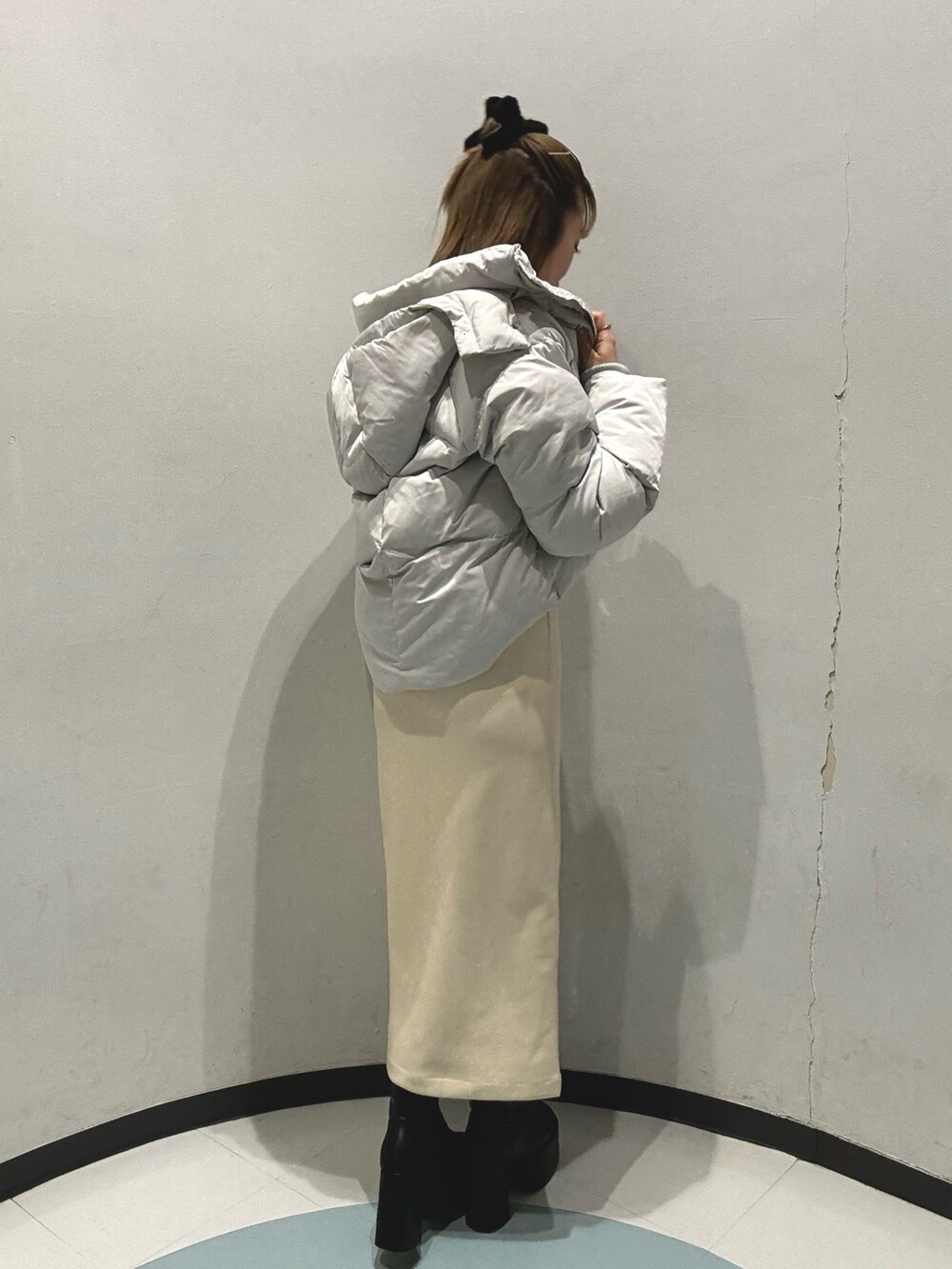 グレー系のダウンジャケット/コート、ホワイト系のニット/セーター、ブラック系のスカートを着用したレディースの秋コーディネートの4枚目の写真