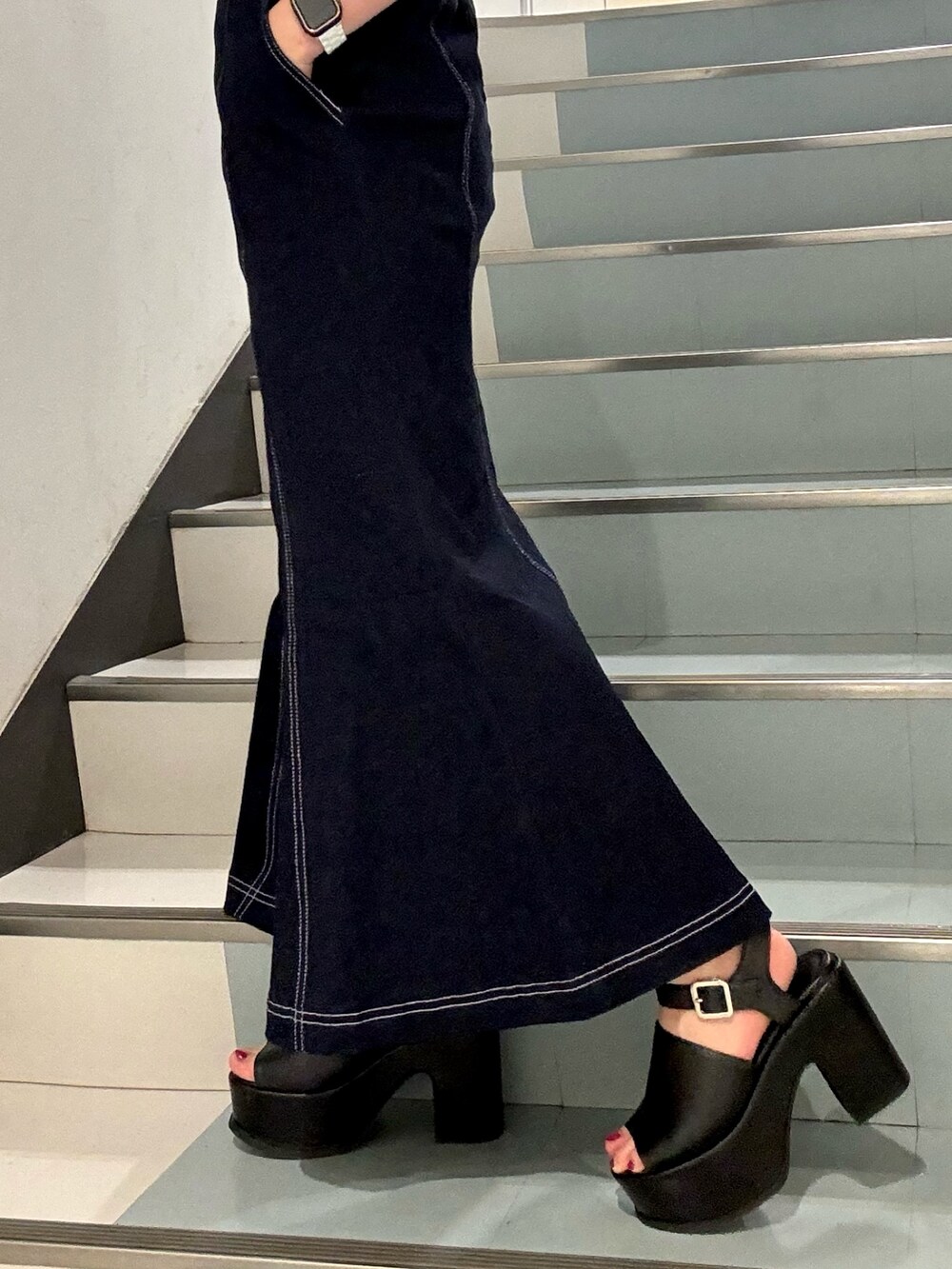 ベージュ系のニット/セーター、ブルー系のジャンパースカート、ブラック系のショルダーバッグを着用したレディースの春コーディネートの5枚目の写真